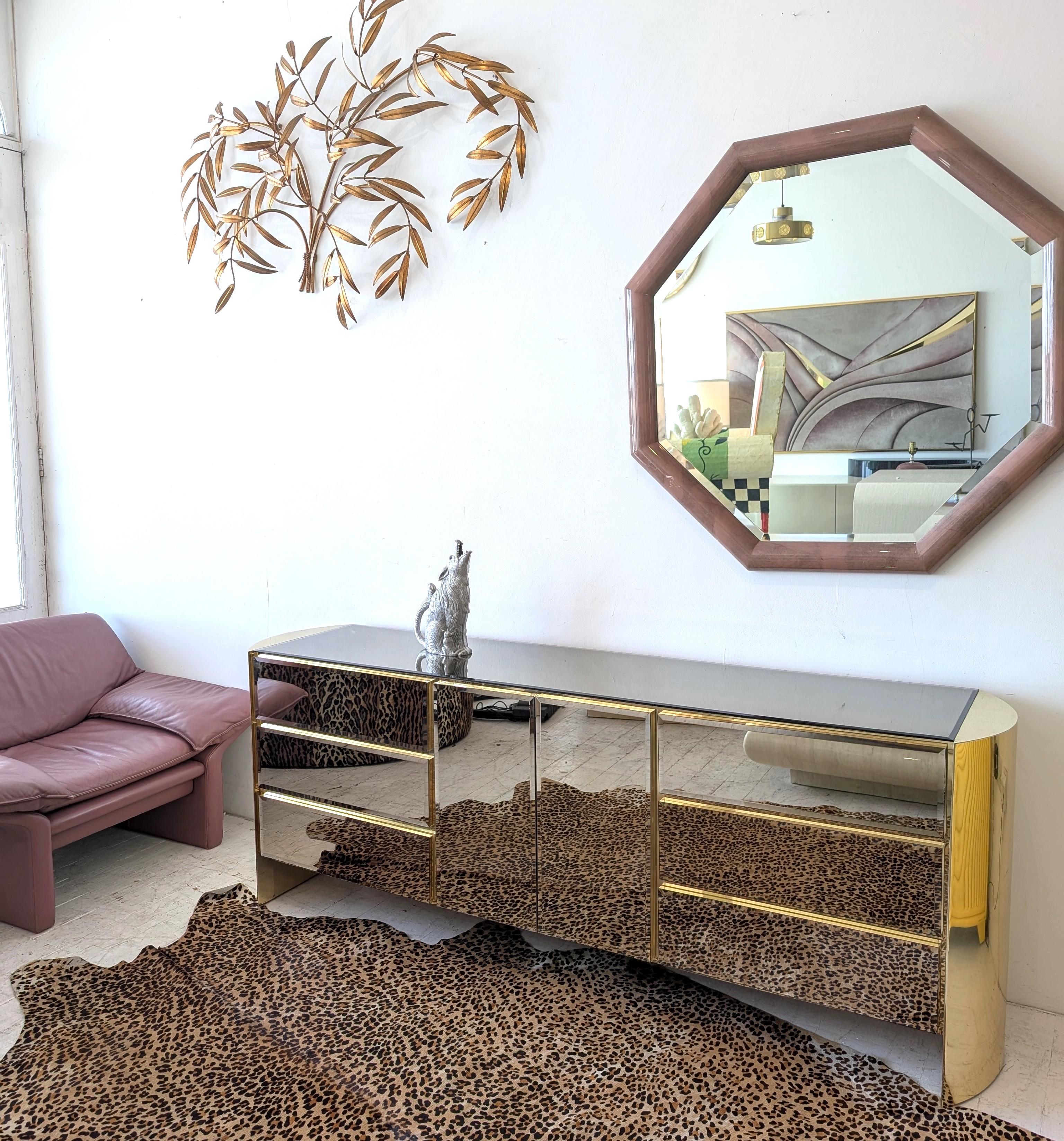 Mirrored glass & gold metal sideboard by Ello, USA 1980s. Bevelled mirror glass drawer & door fronts, and top. The curved ends and all the exterior trim are shiny gold metal. 
Three drawers at each side. The central doors open onto 3 internal