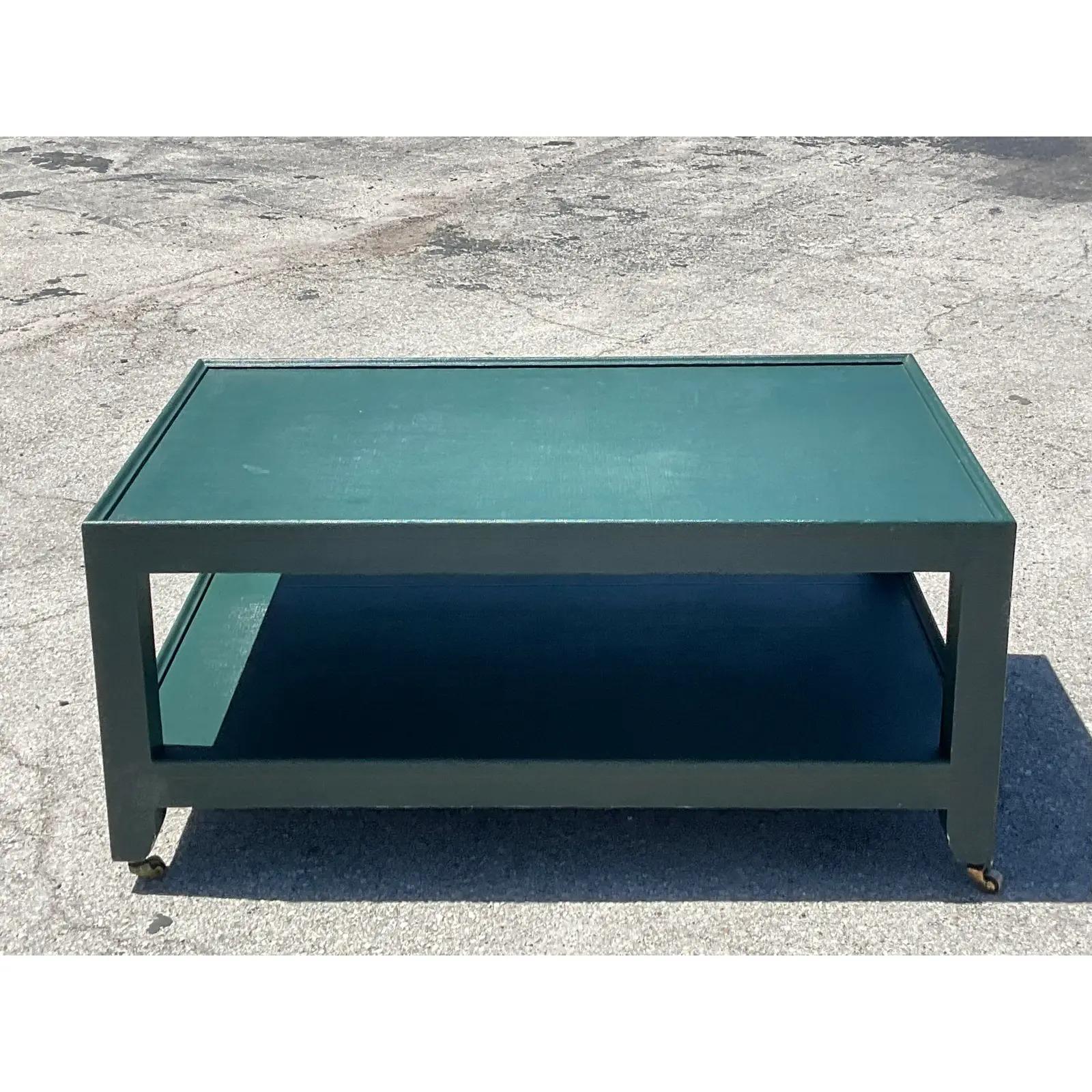 Incredible vintage Postmodern two tiered coffee table. Made by the iconic Karl Springer and signed on the bottom. A deep green lacquer on chic Grasscloth. Easily moves on casters. Acquired from a Gulfstream estate.