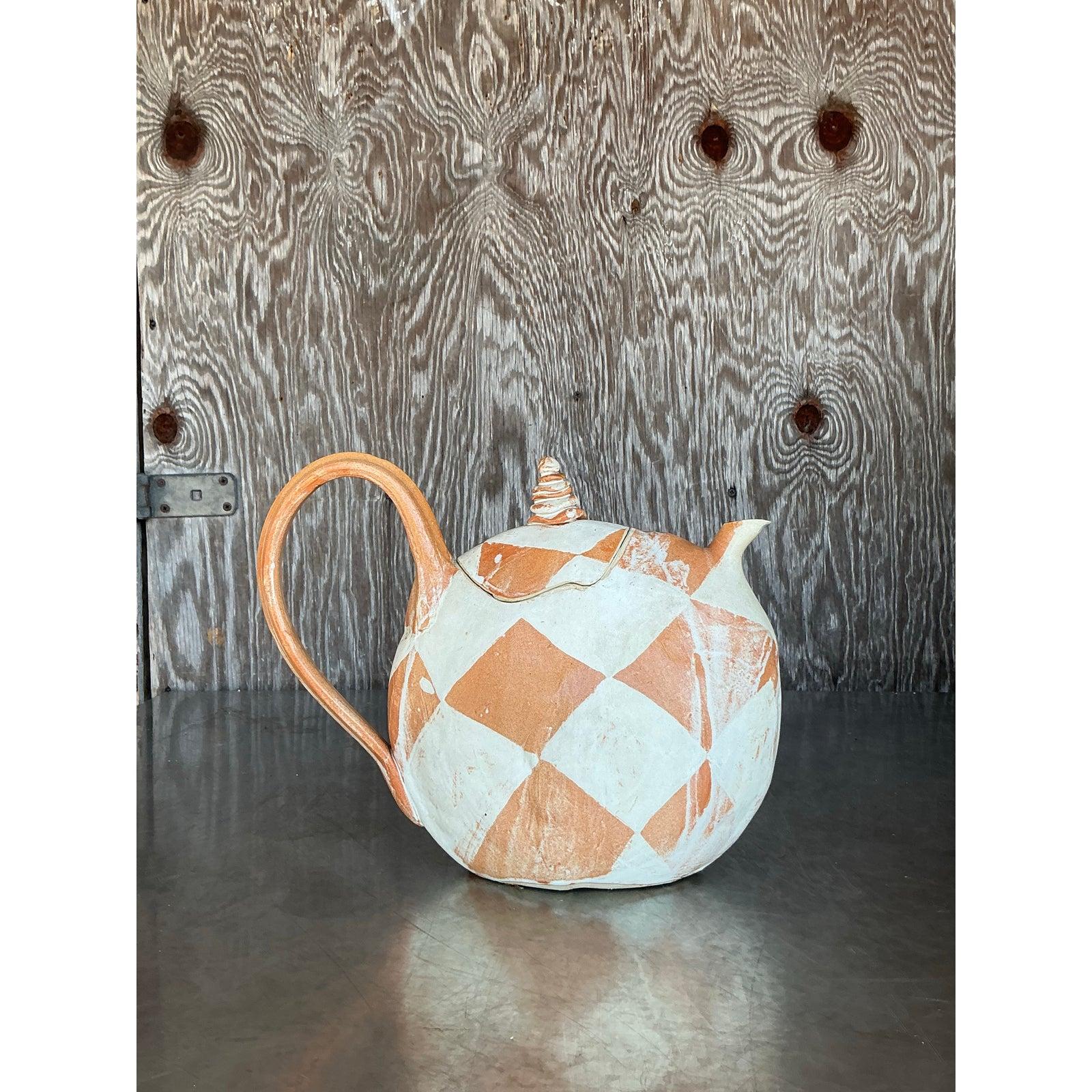 Discover a unique piece of ceramic art with this vintage postmodern studio pottery teapot. Hand-crafted with an expressive form, it features a delightful tonal diamond pattern in earthy terracotta and a creamy white glaze. The playful shape,