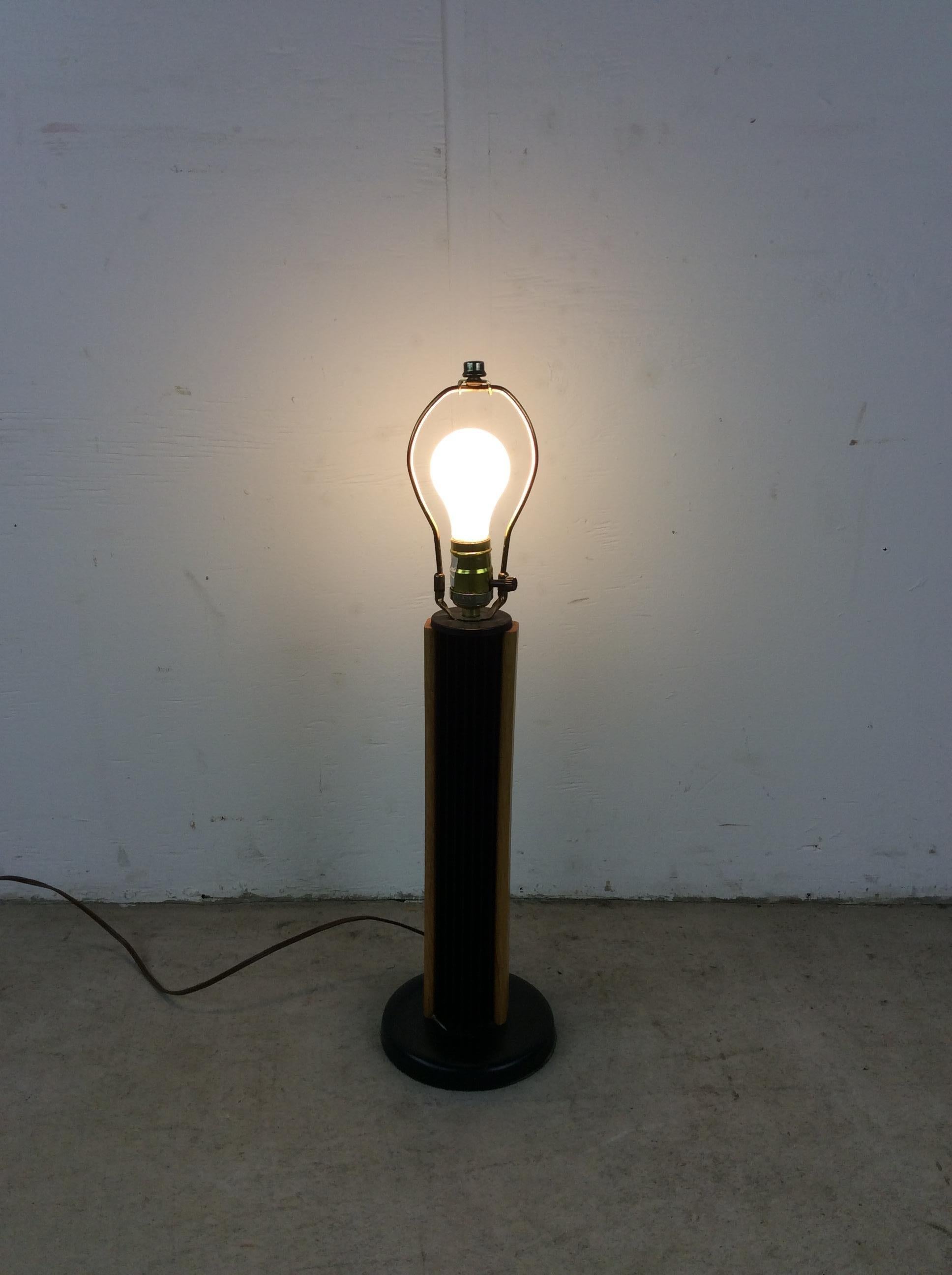 This vintage postmodern table lamp features black metal base with teak wood accents, empire shade, and original vintage cord and wiring.

Dimensions: 18w 18d 24h

Condition: Original finish on teak accents is in good condition. Only minor scuffs,