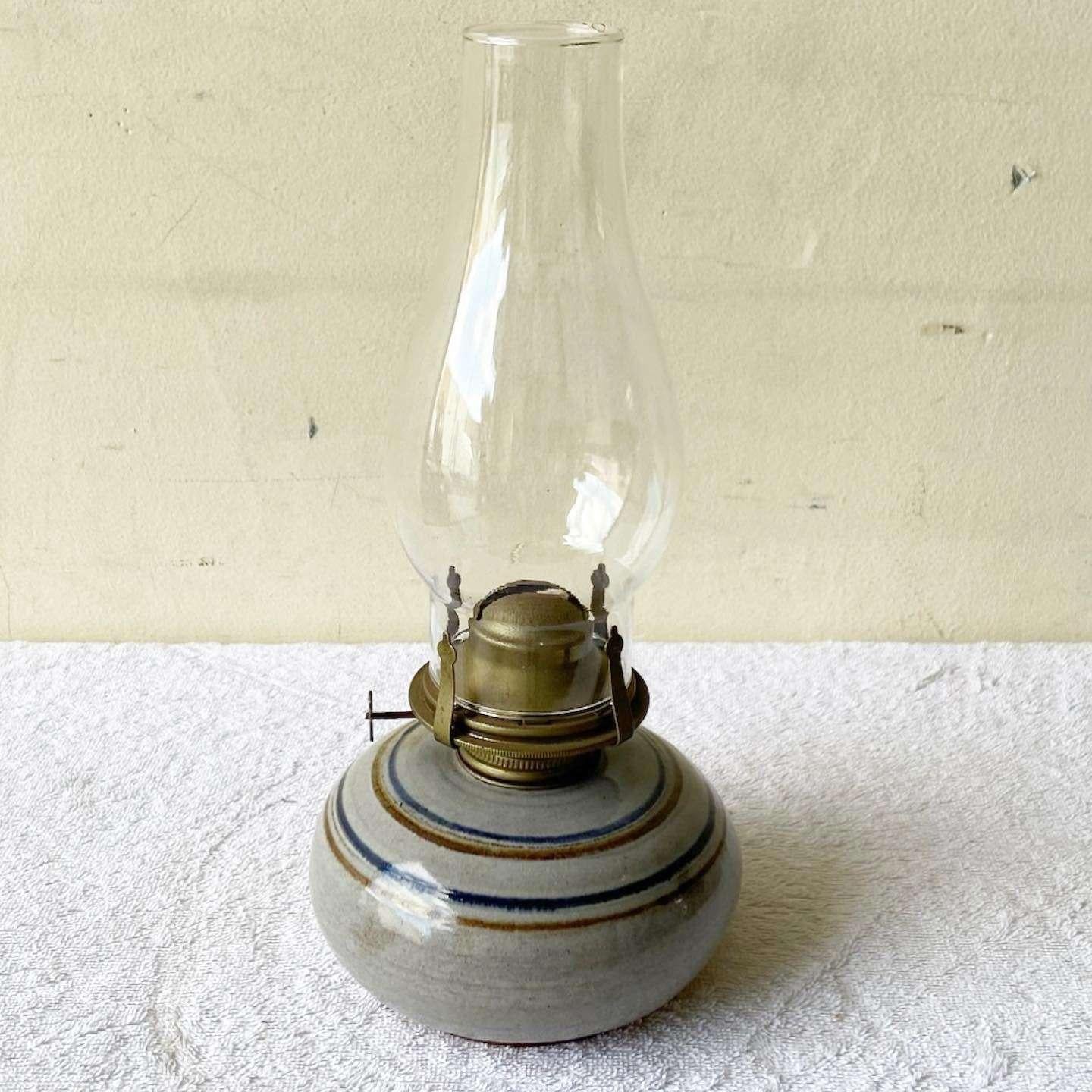 Merveilleuse lampe à huile vintage en poterie du milieu du siècle dernier. Elle est dotée d'une longue mèche fraîche, d'un plateau en verre et d'une finition grise avec des rayures brunes et bleues.