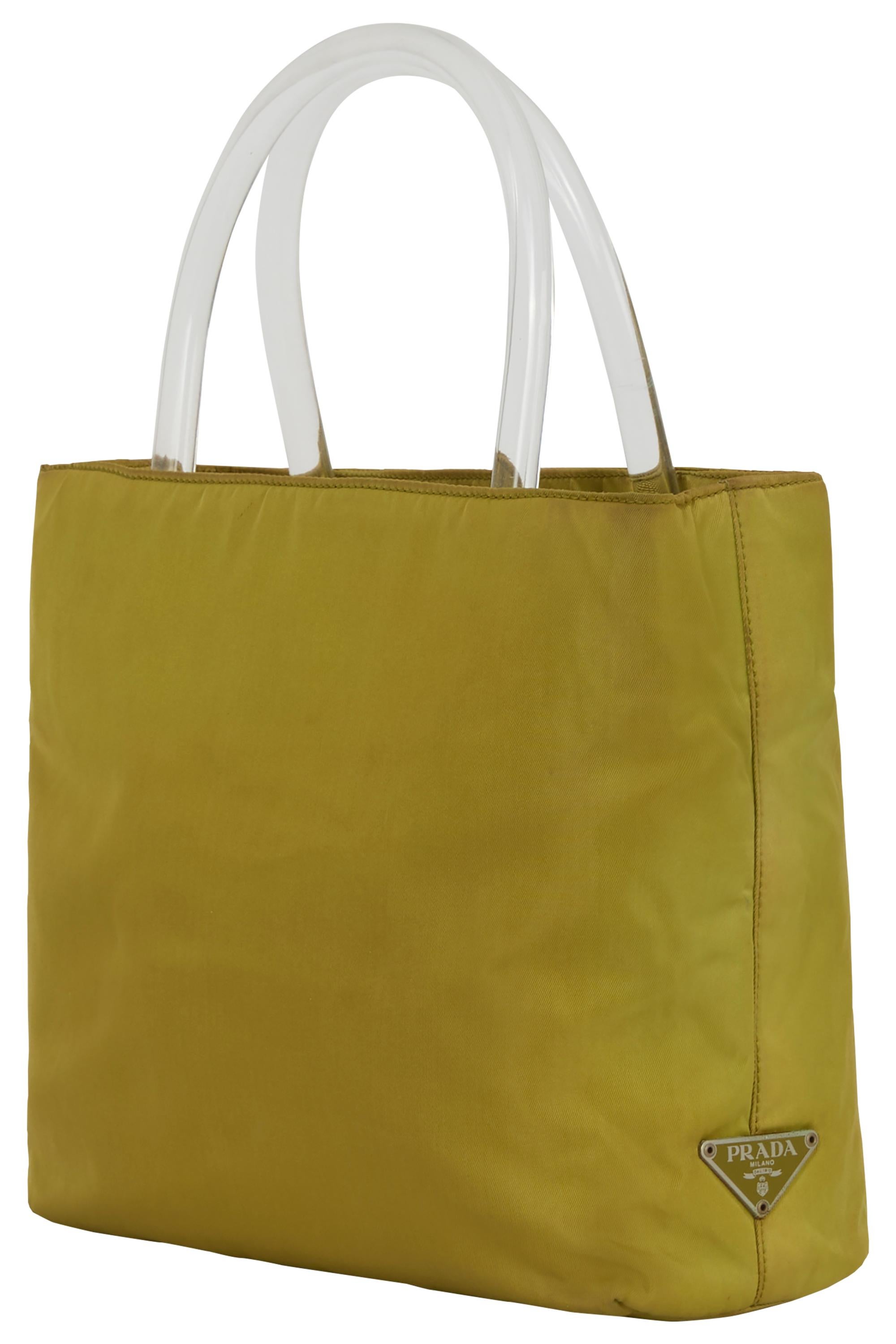 Sac Vintage Prada 1990's en nylon olive. Icone en nylon de couleur olive-moutarde, poignées en acrylique transparent, poids plume.  Il est orné du logo triangulaire émaillé emblématique à la base, de trois compartiments intérieurs différents, dont