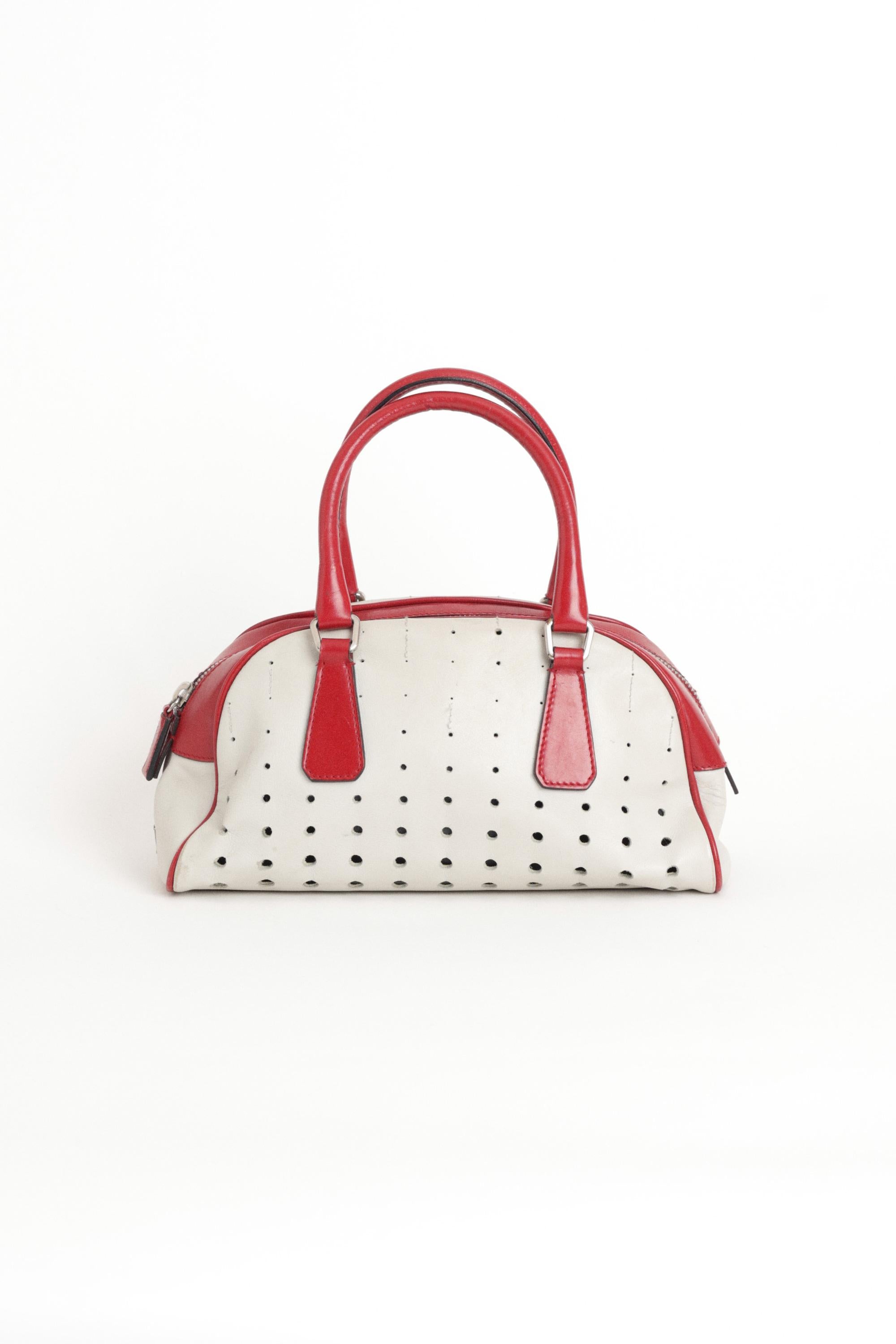 Prada 2000's rot-weiße Bowlingtasche zum Sammeln. Mit perforiertem Design, Innenfach mit Reißverschluss und Reißverschluss. In gutem Vintage-Zustand, das Futter löst sich von der Innenseite.  Sie wurde zu einer der zehn kultigsten Handtaschen aller