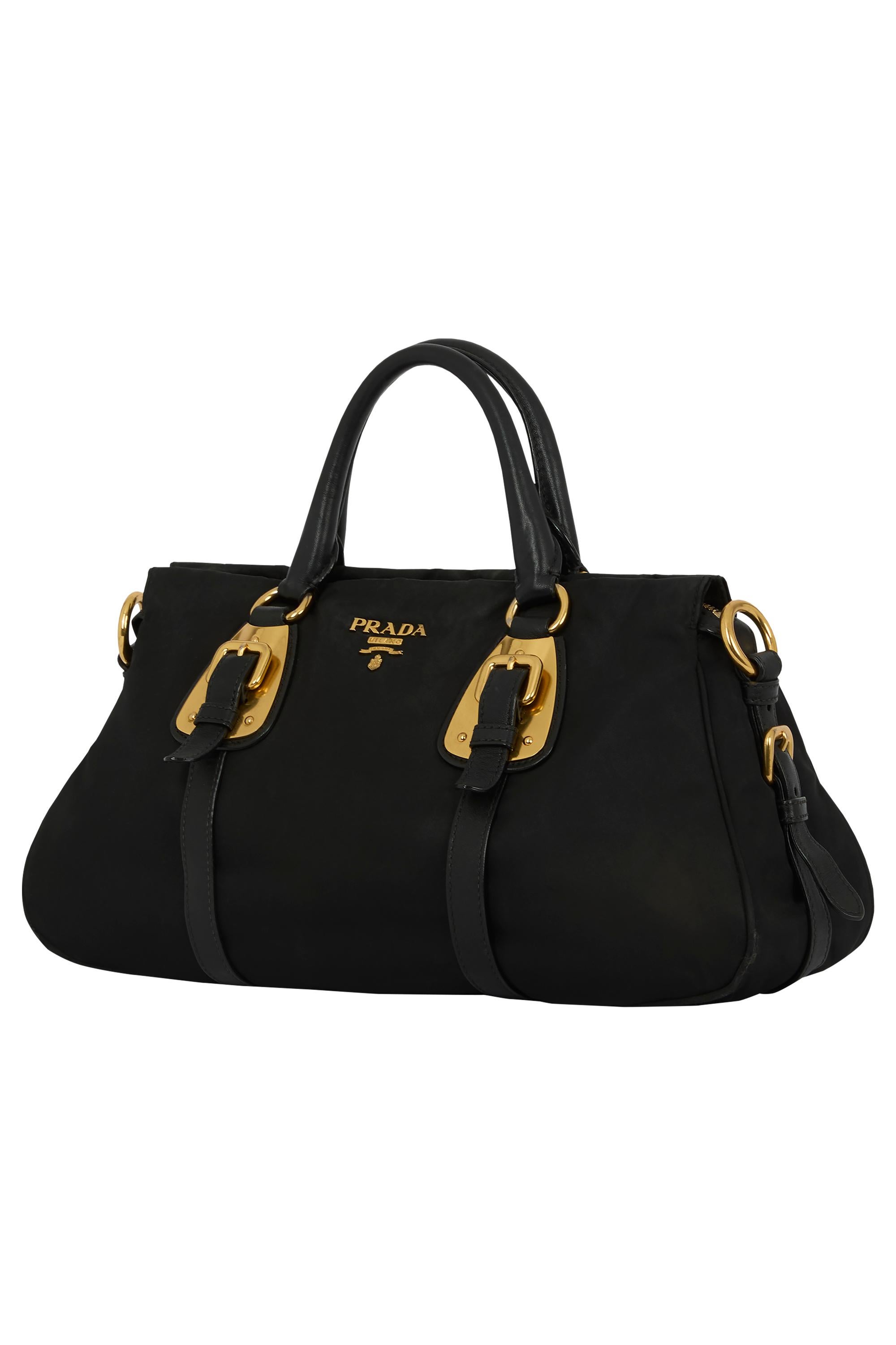  Vintage Prada 2000's sac fourre-tout en nylon noir. Il est composé de nylon noir et d'une garniture en cuir lisse. La silhouette structurée est complétée par une riche quincaillerie dorée, des détails de boucle et deux poignées en cuir roulées.