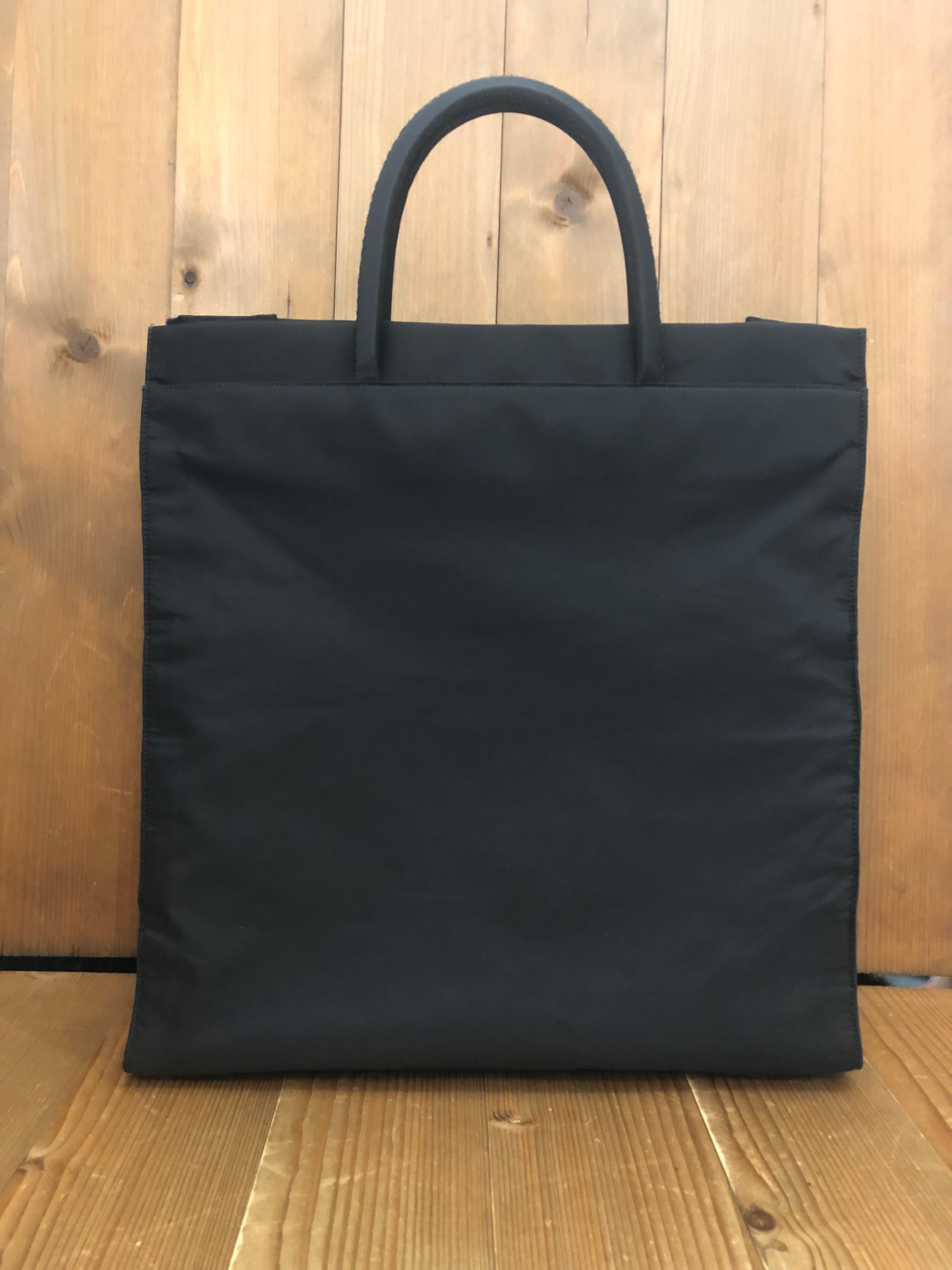 This vintage PRADA book tote bag is crafted of black Tessuto polyester fabric. This minimalist chic Prada book tote features two front pockets with Velcro closure and two side open pockets. Wide top opens up to a spacious compartment with a zippered