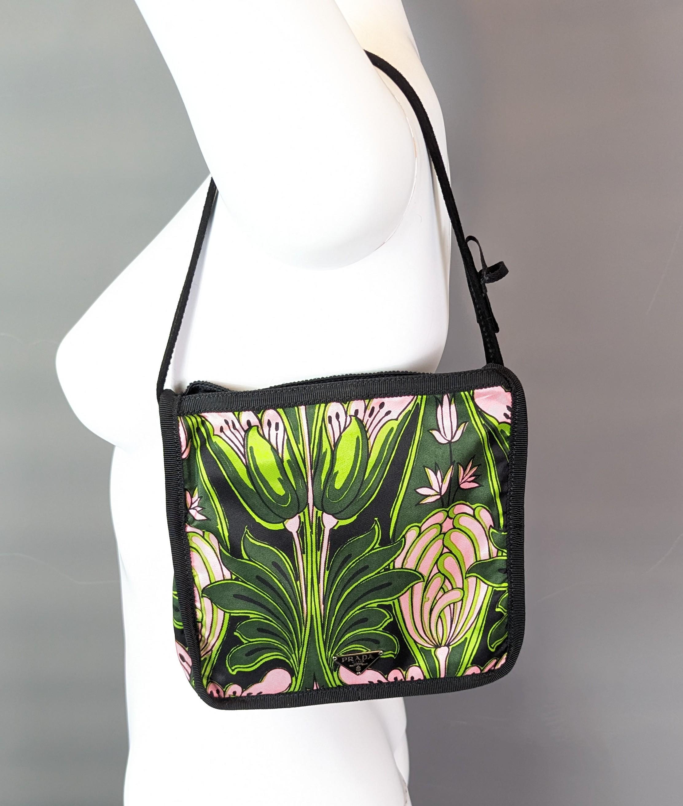 Un precioso y vibrante bolso Prada vintage.

Fabricada en sarga de lona sedosa con un estampado floral de estilo Art Nouveau en vivos verdes y rosas sobre fondo negro.

Lleva la marca en una etiqueta metálica plateada en la parte delantera y también