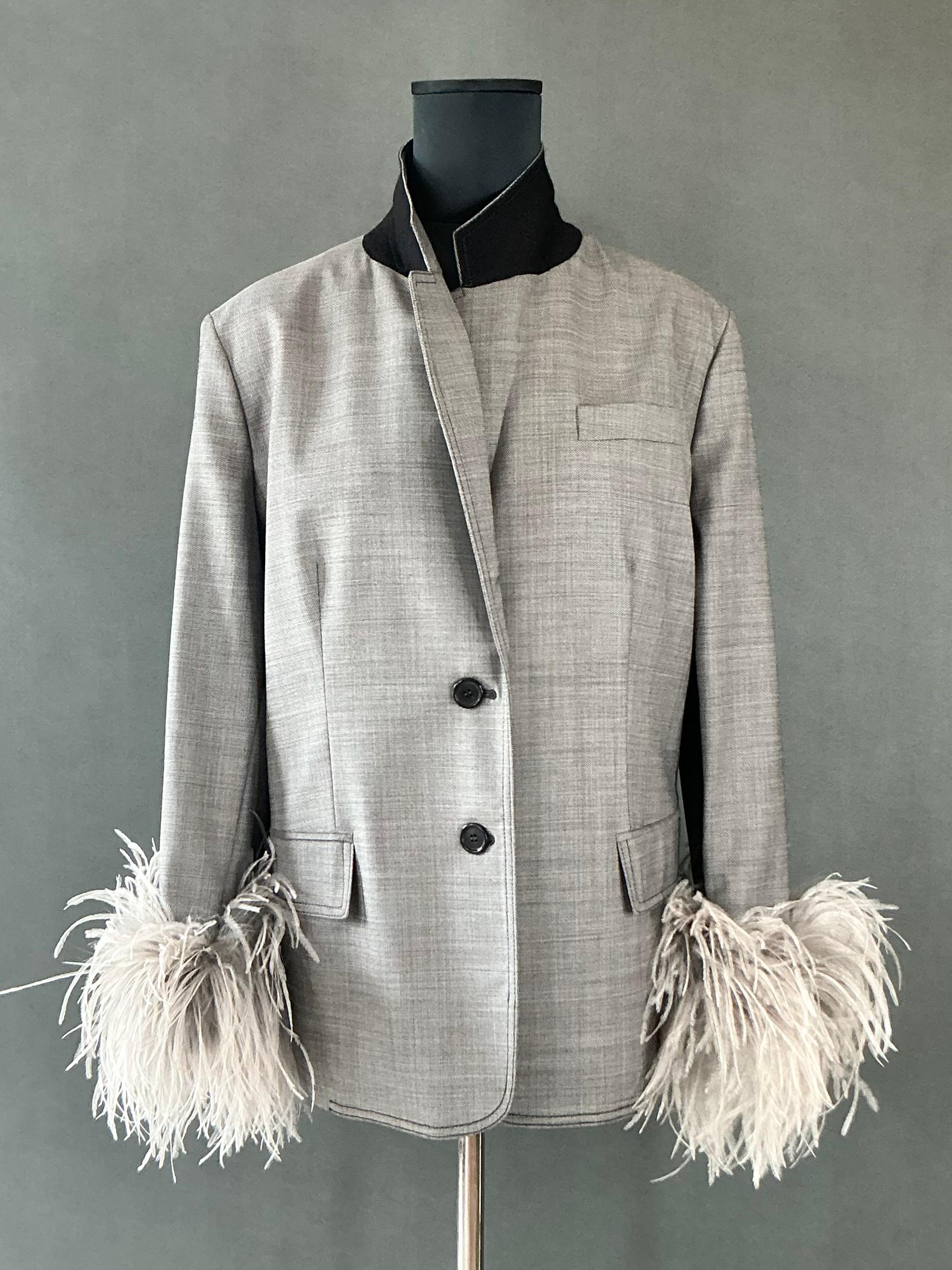 Vintage Prada Fil-A-Fil Feather Cuff Blazer is a luxurious and unique piece that showcases Prada's signature blend of high fashion, elegance, and bold innovation. Known for their forward-thinking designs and impeccable tailoring, Prada has made a