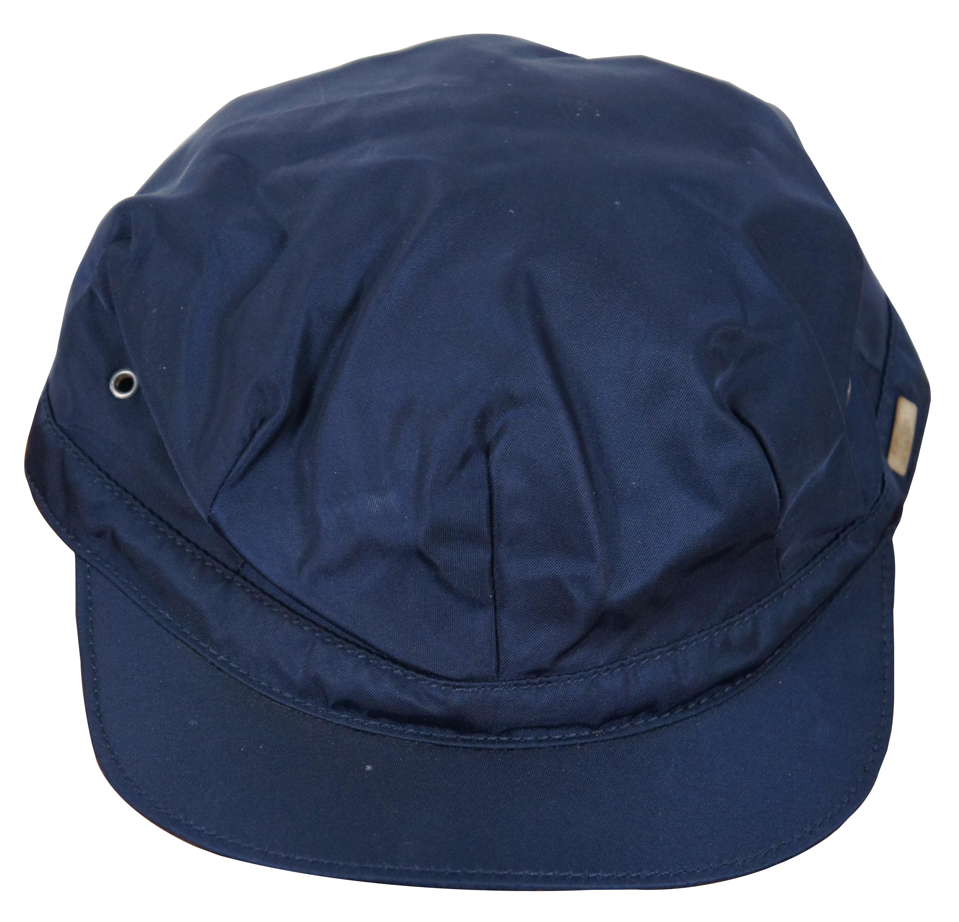 Rare vintage short brim Prada navy blue polymide cycling / fisherman / train conductor style cap / hat with eyelet accents.

Size M / 7” x 8.5” x 3.5” / Approx Circumference – 22
