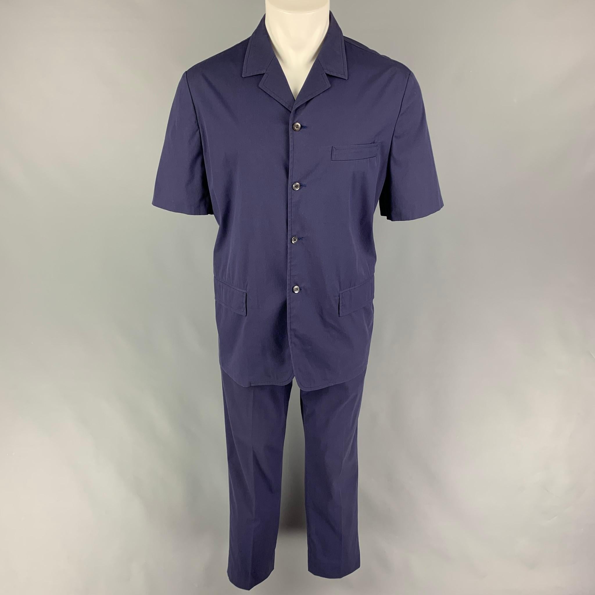 Vintage PRADA 2 Piece set comes in a navy cotton featuring a camp collar, flap pocket, short sleeves, loose fit buttoned shirt, and matching flat front trousers. Made in Italy. 

Very Good Pre-Owned Condition.
Marked: