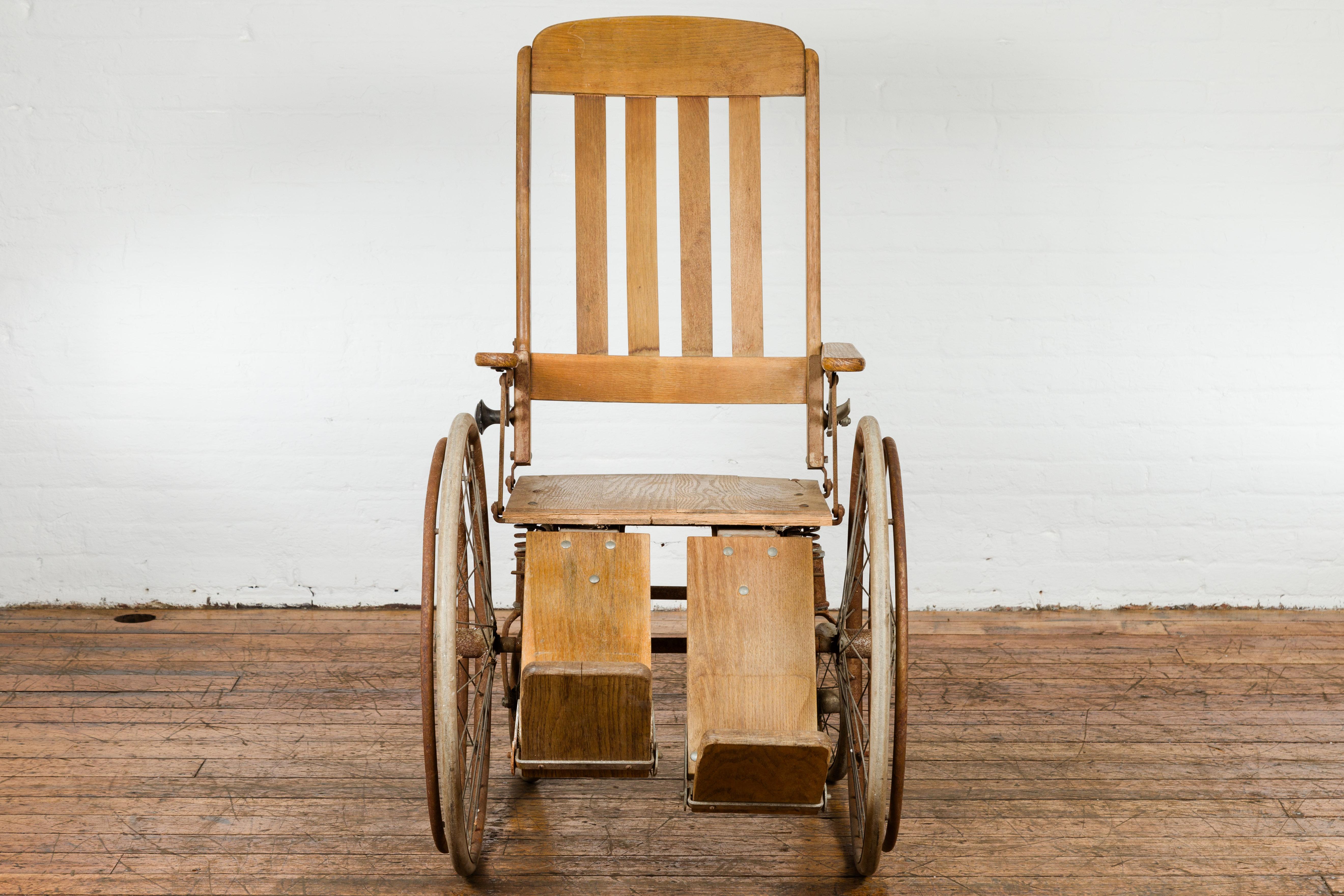 A vintage light brown wooden wheelchair, sporting a label in the back 
