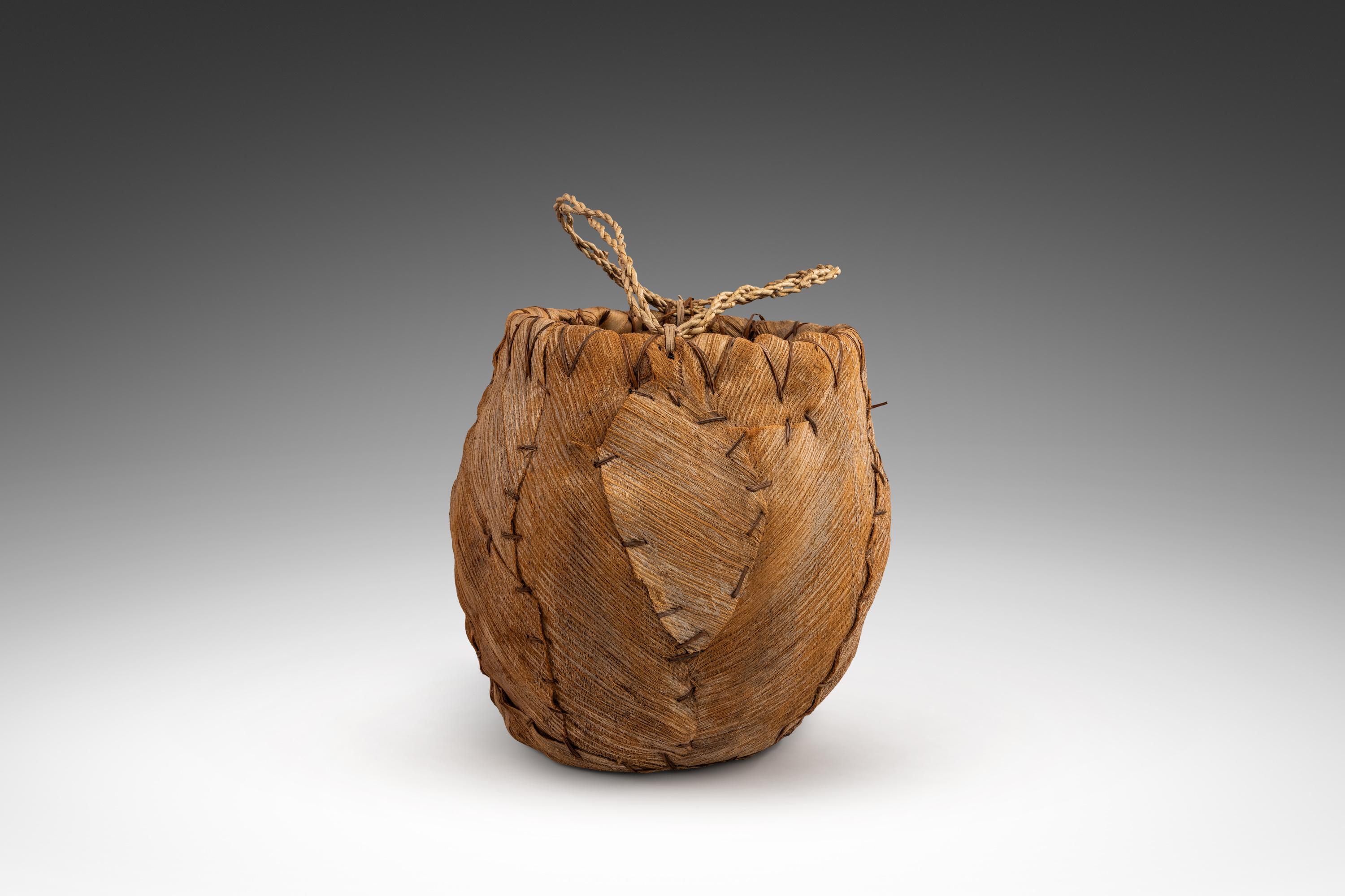 Ein faszinierender primitiver, handgeflochtener Korb aus Palmenrinde voller Charme und Handwerkskunst aus der alten Welt. Mit einem inneren Rahmen aus Weinrebenrinde und einer äußeren Verkleidung aus geflochtener Palmenrinde kann dieses