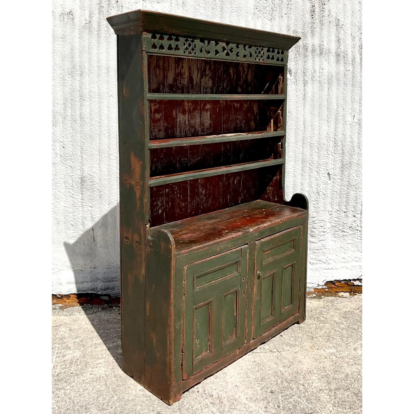 Stunning vintage Irish Rustic China cabinet. Hand made from a rustic distressed wood with a deep green color. Lots of great patina from time. Acquired from a Palm Beach estate.

The cabinet is in great vintage condition. Scuffs, cracks and blemishes