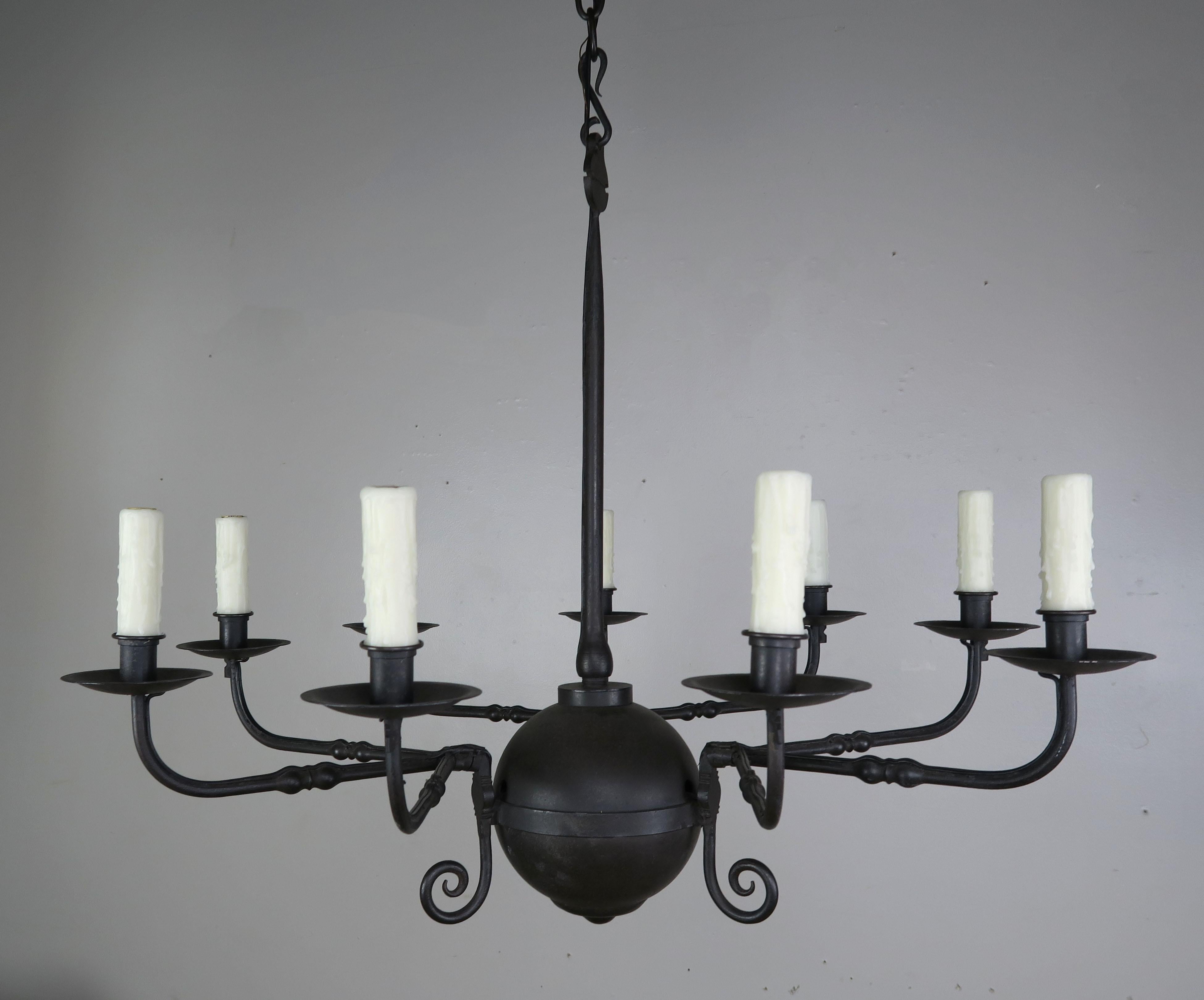 Vintage primitive style wrought iron 9-light chandelier by Paul Ferrante. The chandelier has a center sphere shape surrounded by hand wrought iron arms grouped in three and detailed with center knots. The fixture has been newly rewired with drip wax