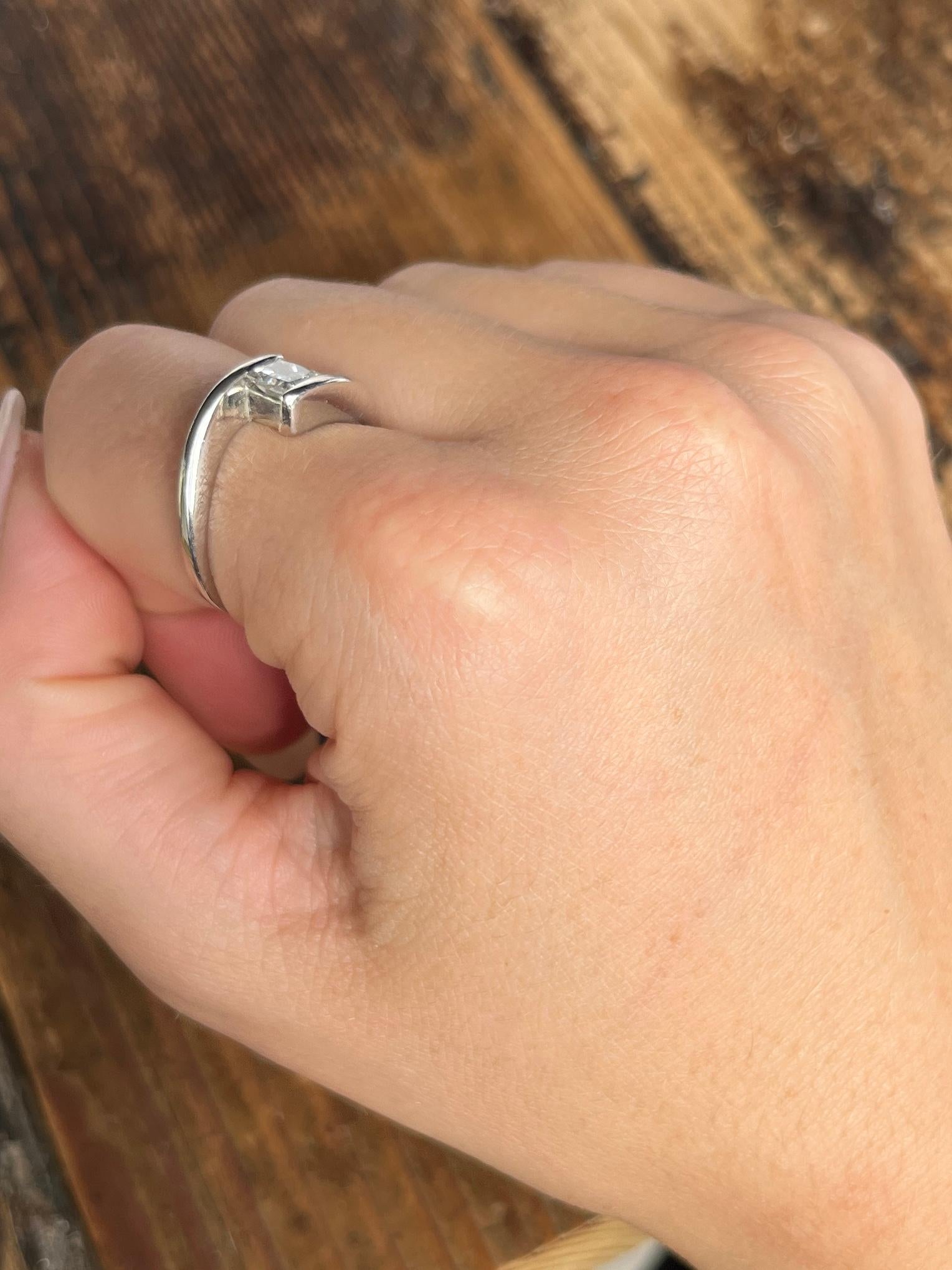 Le diamant de taille princesse de cette bague mesure 40pts et est vraiment magnifique. Il est de couleur H et présente un éclat magnifique. L'anneau de platine est enveloppant et maintient le diamant entre les extrémités de l'anneau croisé. 

Taille