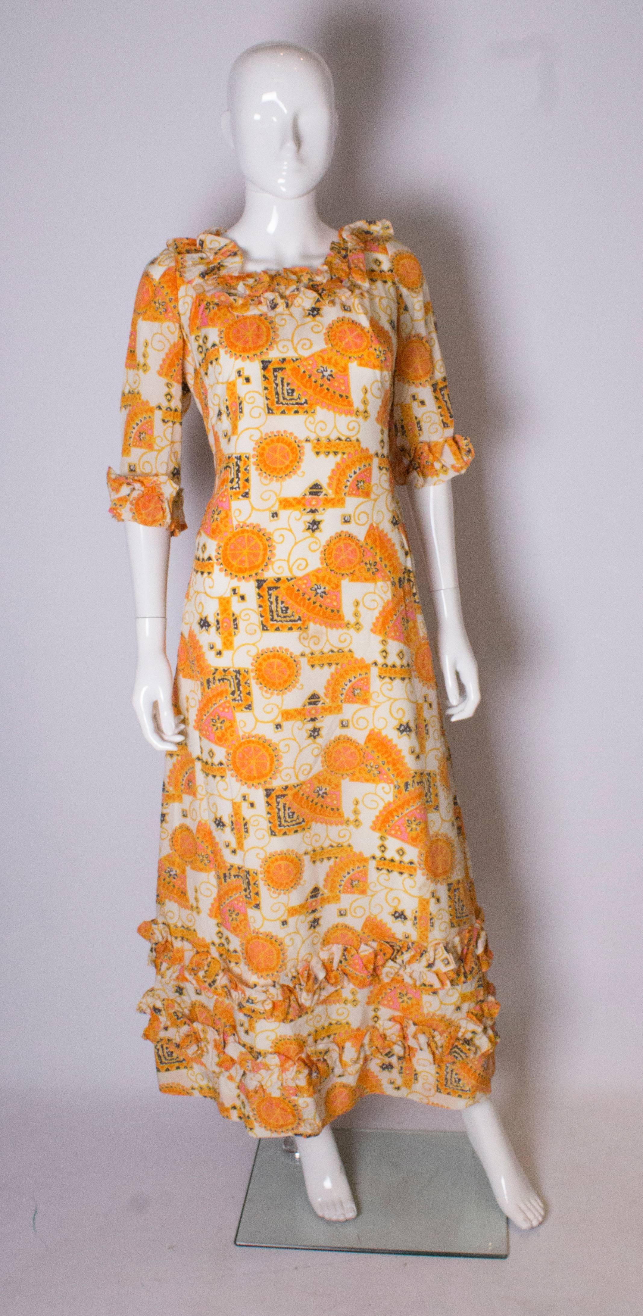 Una gran  Vestido vintage para el verano, de Binnie London. En un maravilloso estampado veraniego, en naranja, negro y dorado. El vestido tiene volantes alrededor del cuello y  2 filas en el  dobladillo. Está totalmente forrado y tiene una