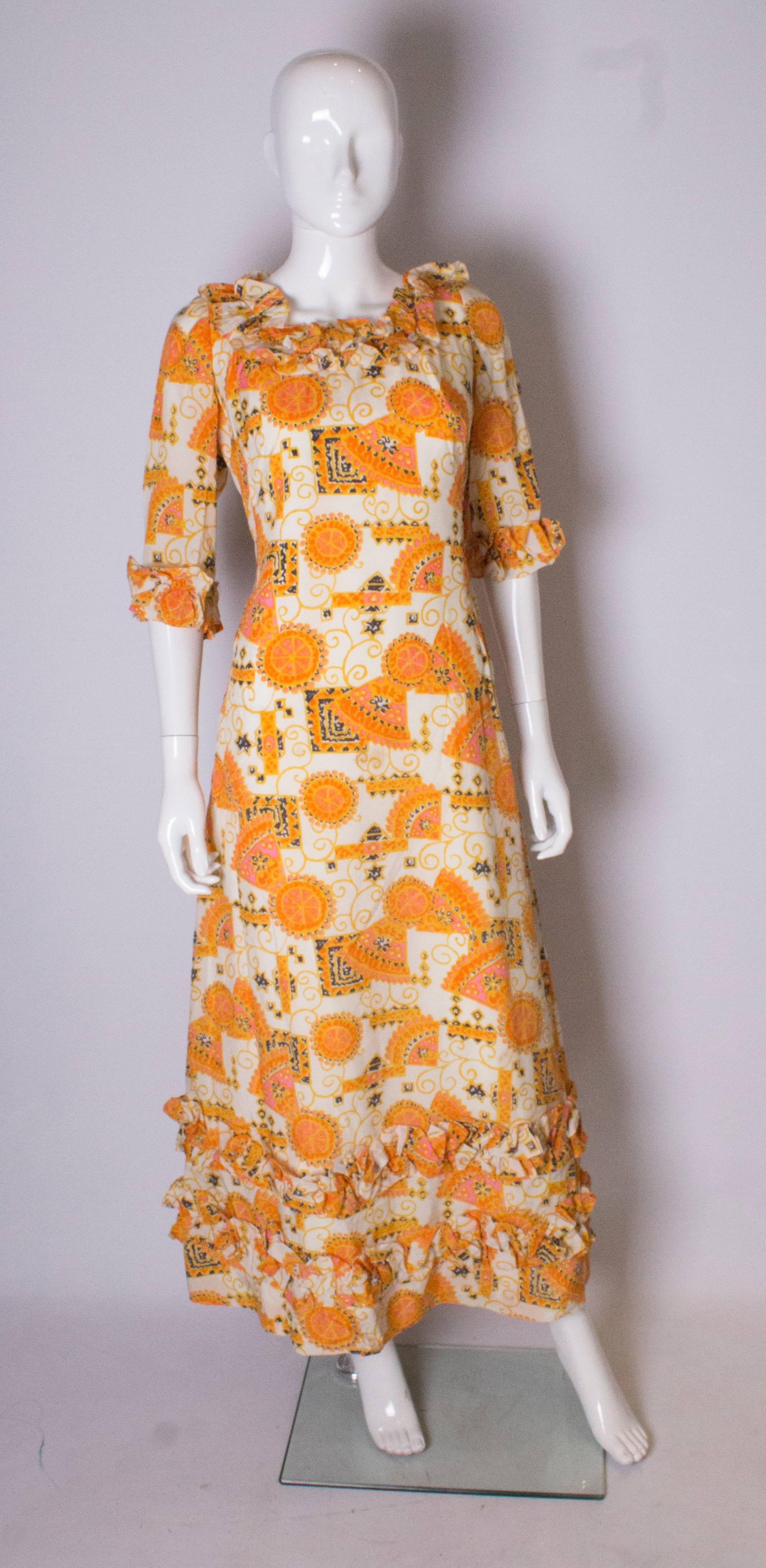 A great  vintage gown for Summer , by Binnie London. In a wonderful summer print, in orange, black and gold. The dress has ruffles around the neck and  2 rows on the  hem. It is fully lined, and has a central back zip.