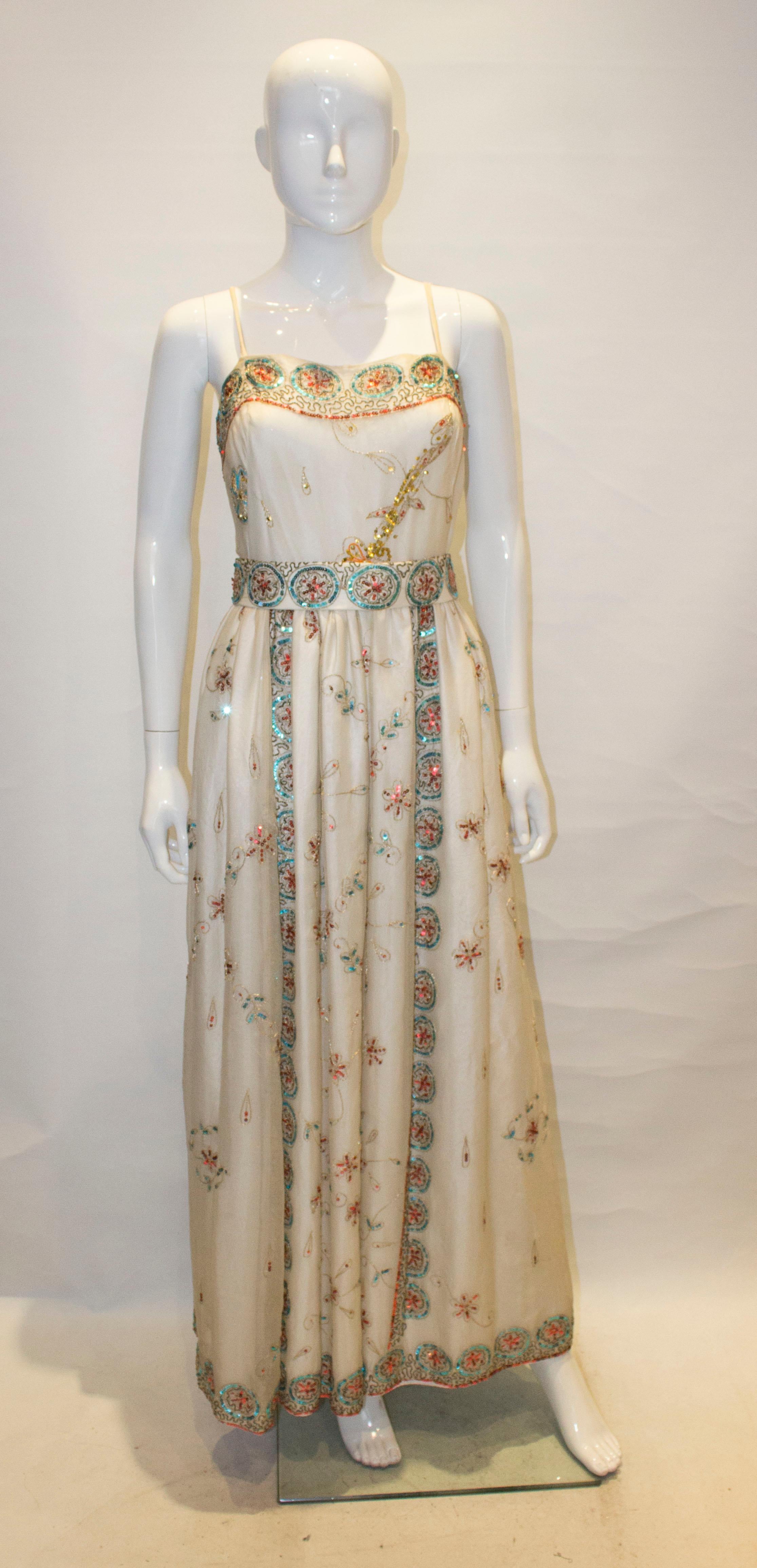 A pretty vintage gown by Profils du Monde of Beverly Hills , California.  The dress is in a white silk with sequin decoration, and has spagetti straps and a marching belt. The dress is fully lined and has a central back zip.