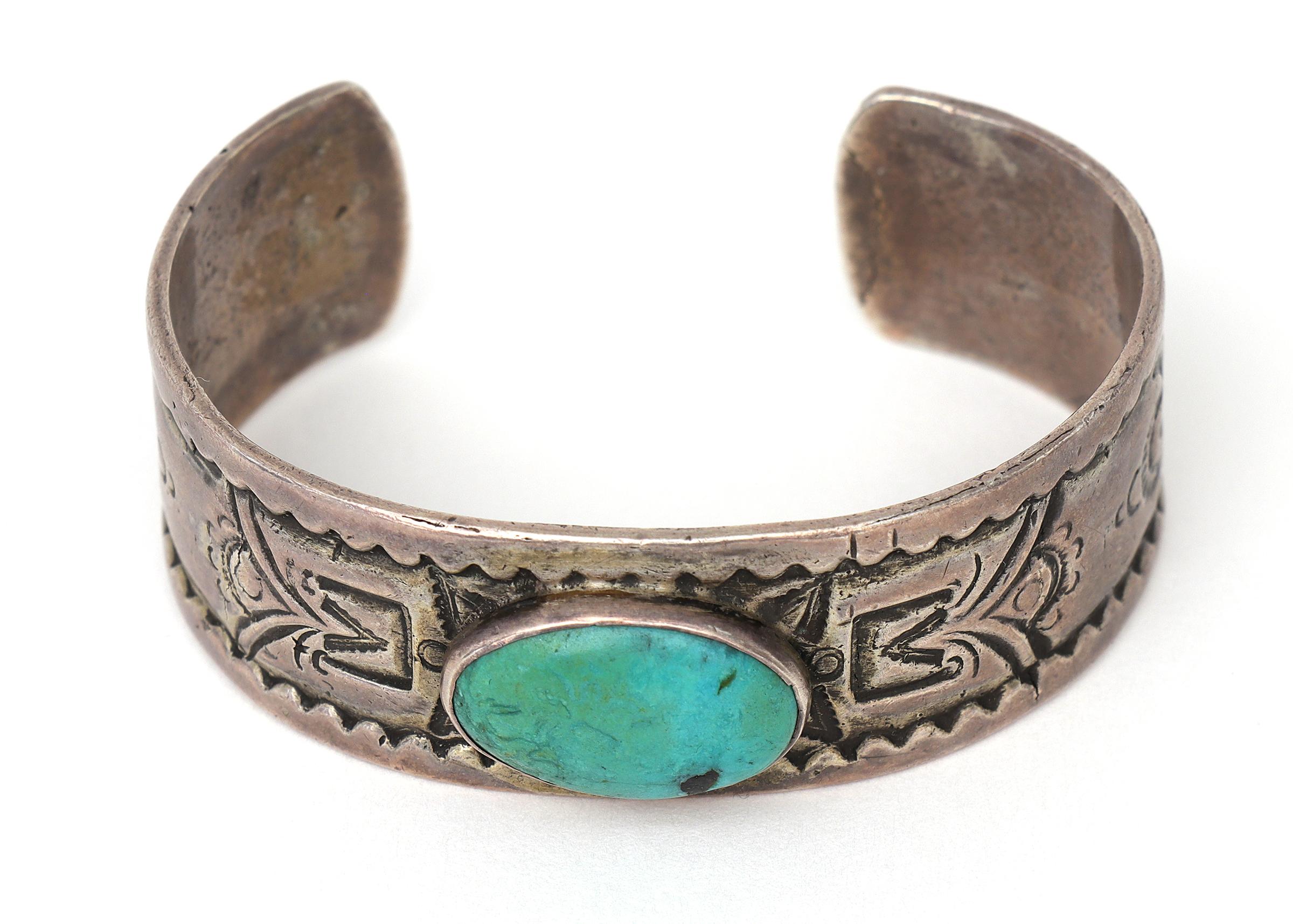 Vintage Southwestern Native American Pueblo Old Pawn cuff bracelet, circa 1915. Stamped ingot silver with a turquoise cabochon. The inner bracelet circumference measures approximately 5 ½ inches with an opening measuring 1 ¼ inches (6 ¾ inches total