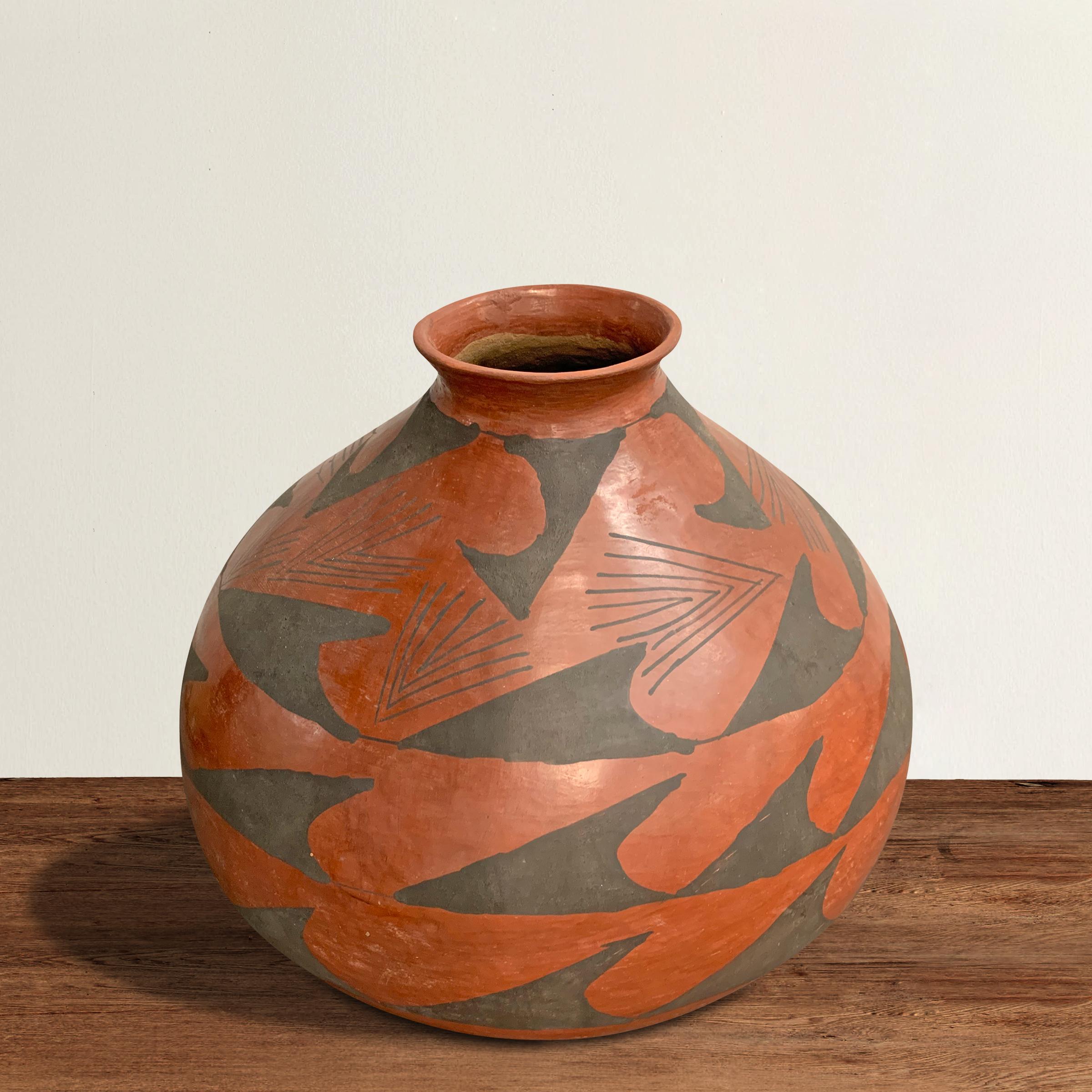 A striking vintage native American pueblo pottery vase with a narrow neck and a wide belly, and decorated with an all-over geometric pattern and a stylized pine needle pattern around the top portion of the vase. Not signed.