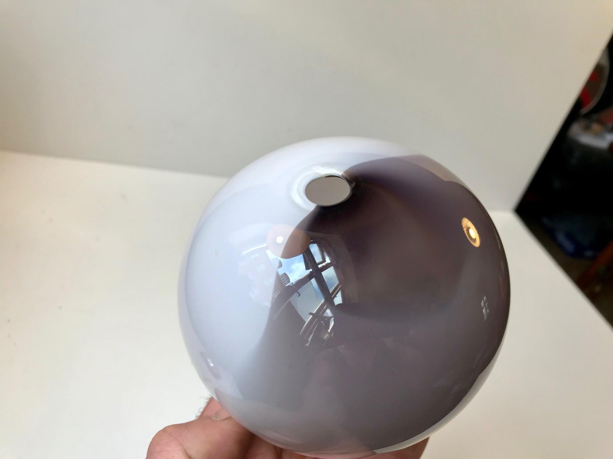 This ball shaped vase is made of hand blown glass. One half is in purple and one half is in white opaline glass. Its signed by hand by the maker and designer (RG) and dated 1984.