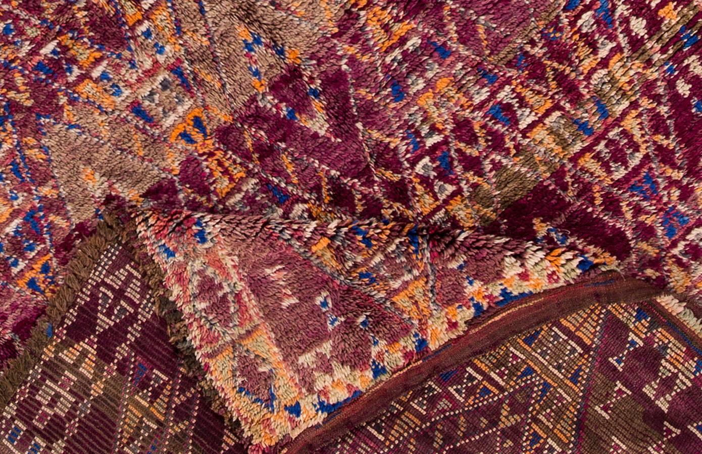 Schöner marokkanischer Vintage-Teppich. Dieses Stück hat ein aubergine-lila Feld mit einem geometrischen Muster aus sich kreuzenden Rauten. Durchgehend graue und orangefarbene Akzente. 
Dieser Teppich misst: 5'07