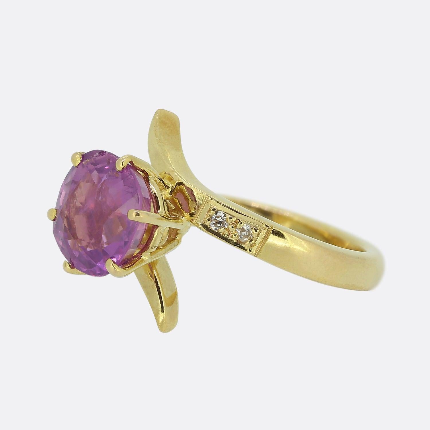 Here we have a wonderfully original vintage piece. Focally, this ring showcases a single 2.00ct round faceted purple sapphire. This principle stones sits proud atop a swirling diamond set backdrop and an otherwise plain polished 18ct yellow gold