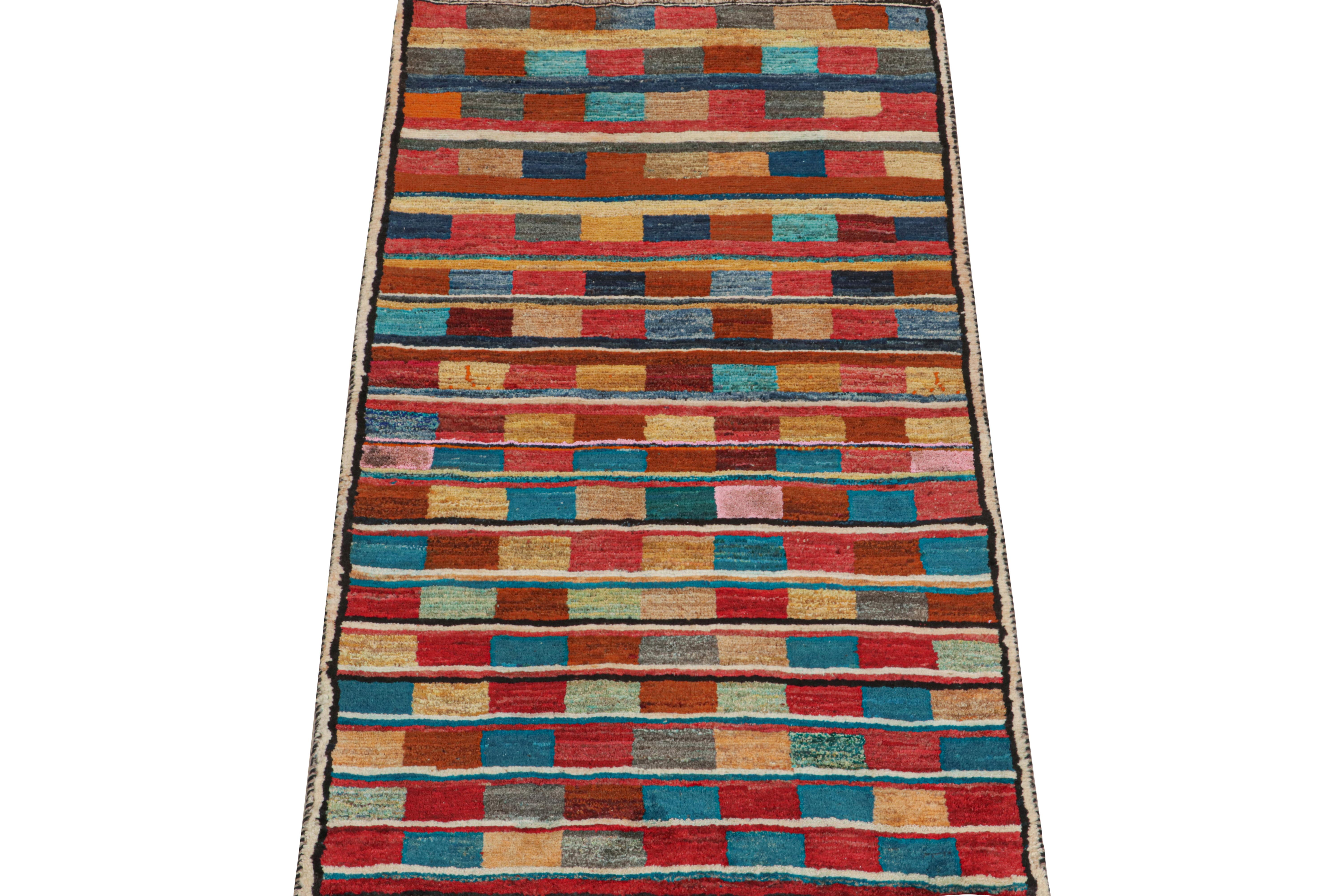 This vintage 3x6 Persian runner is a Gabbeh rug that originates from the Qashqai tribe—hand-knotted in wool circa 1950-1960.

Its geometric pattern of squares and stripes enjoys vibrant polychromatic colors—particularly red, blue, brown, and gold