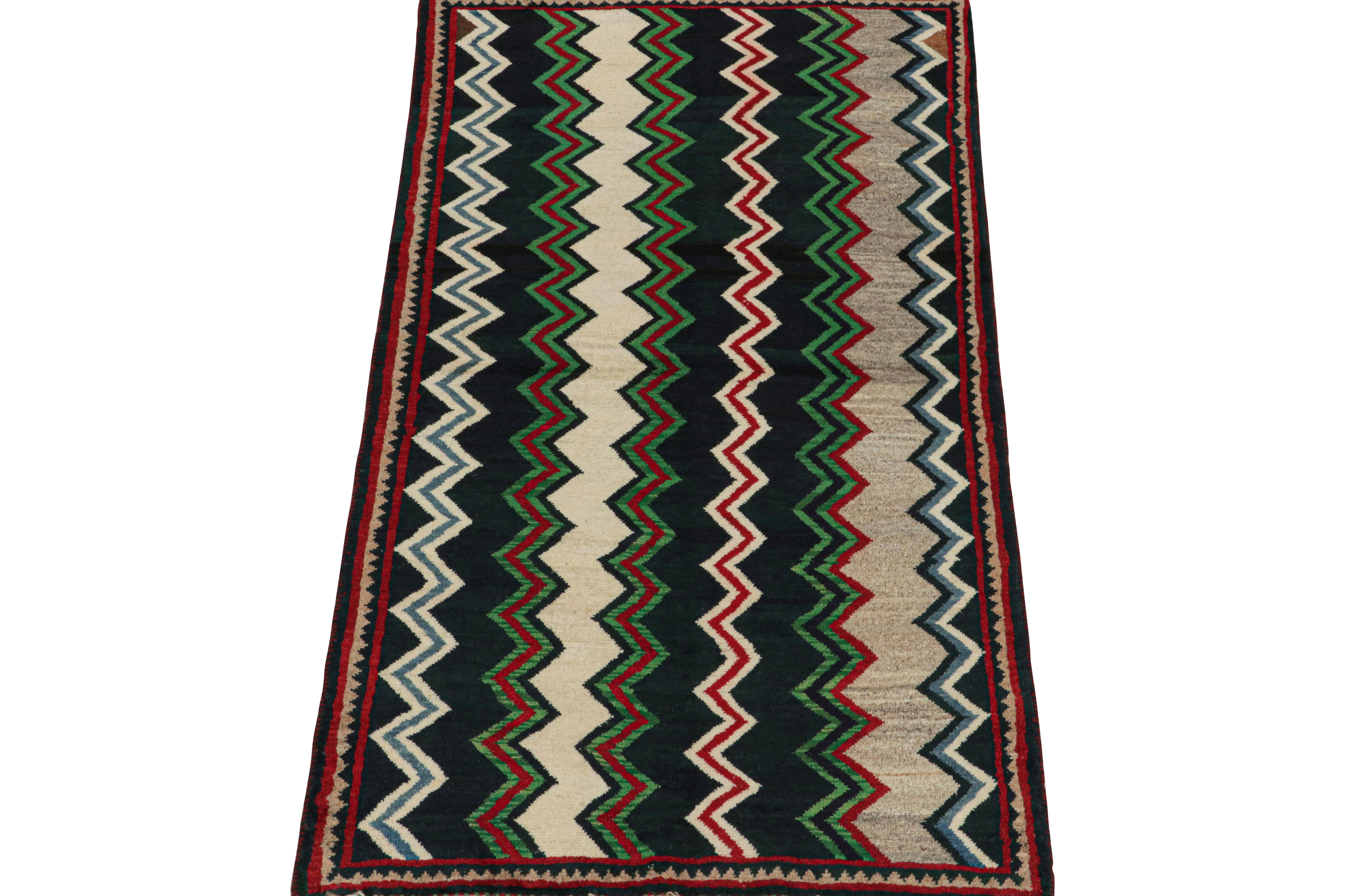 This vintage 3x6 Persian runner is a Gabbeh rug that originates from the Qashqai tribe—hand-knotted in wool circa 1950-1960.

Its geometric pattern is a repeat of chevrons in navy blue, green, red, and beige tones with sharp lines. 
Connoisseurs