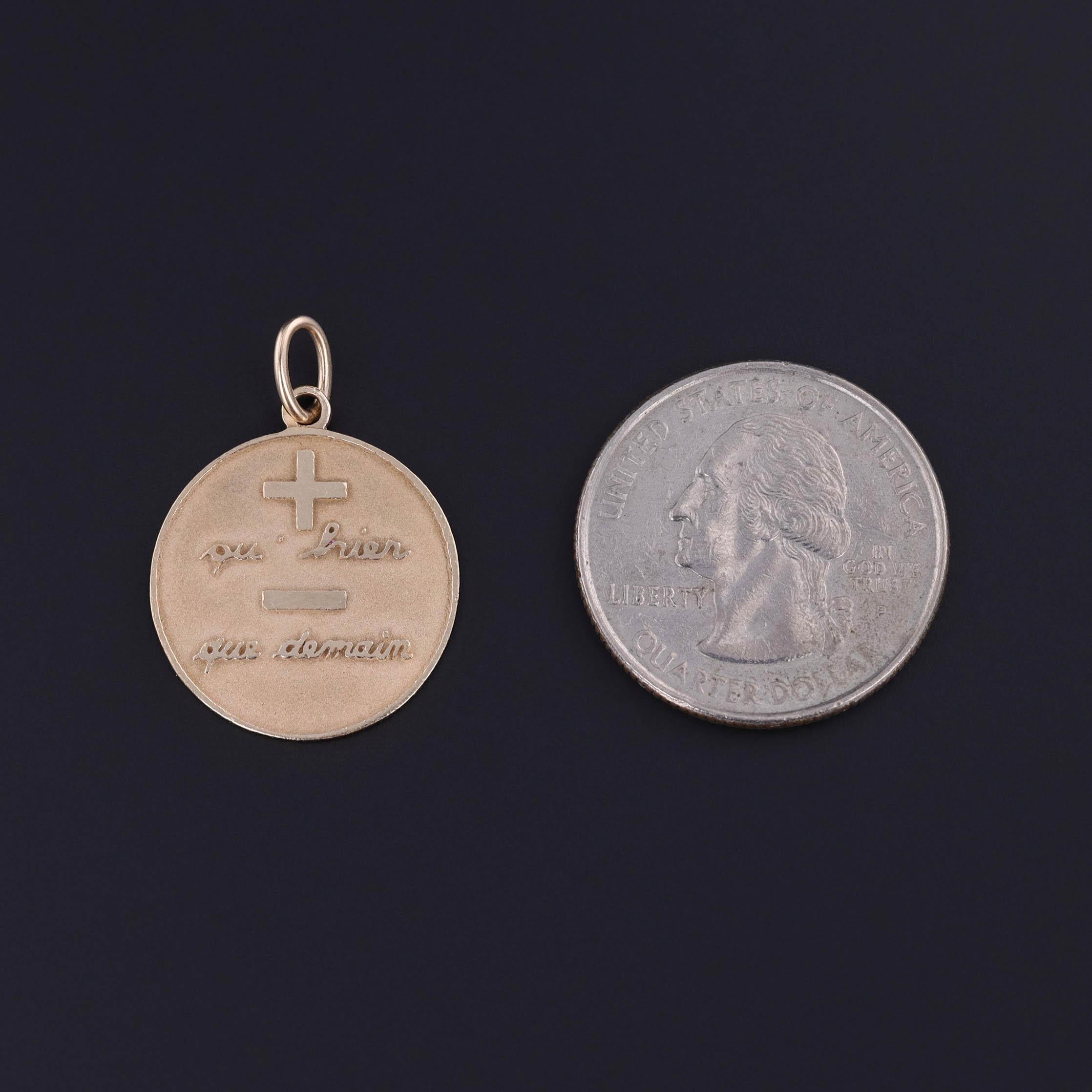 A vintage pendant of 14k gold from 1980, featuring the French phrase 'qu' hier de demain' which translates to 