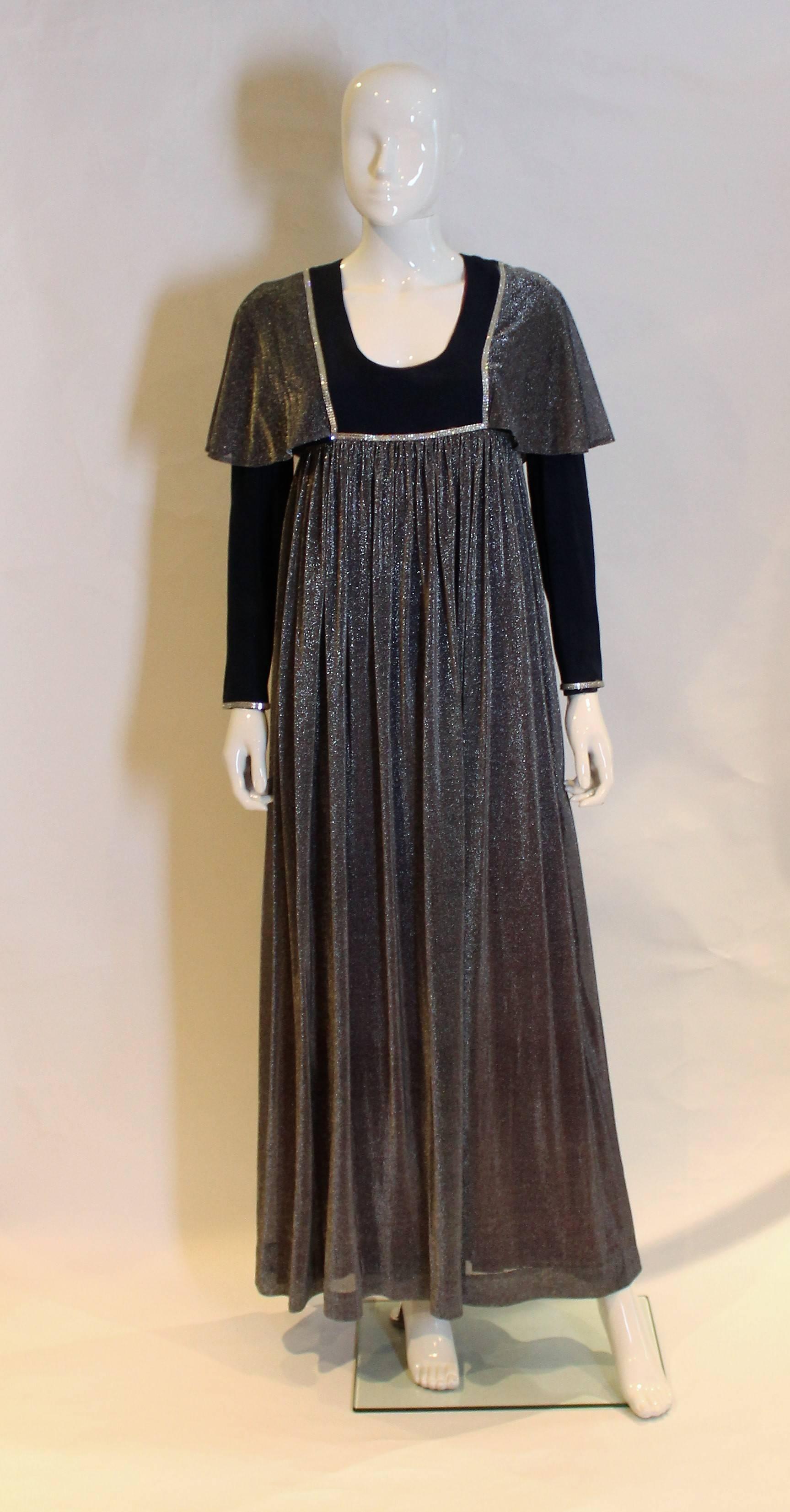 A blue vintage boho gown by Quad. The gown has a deep  neckline, long sleeves and diamante trim. It is fully lined.