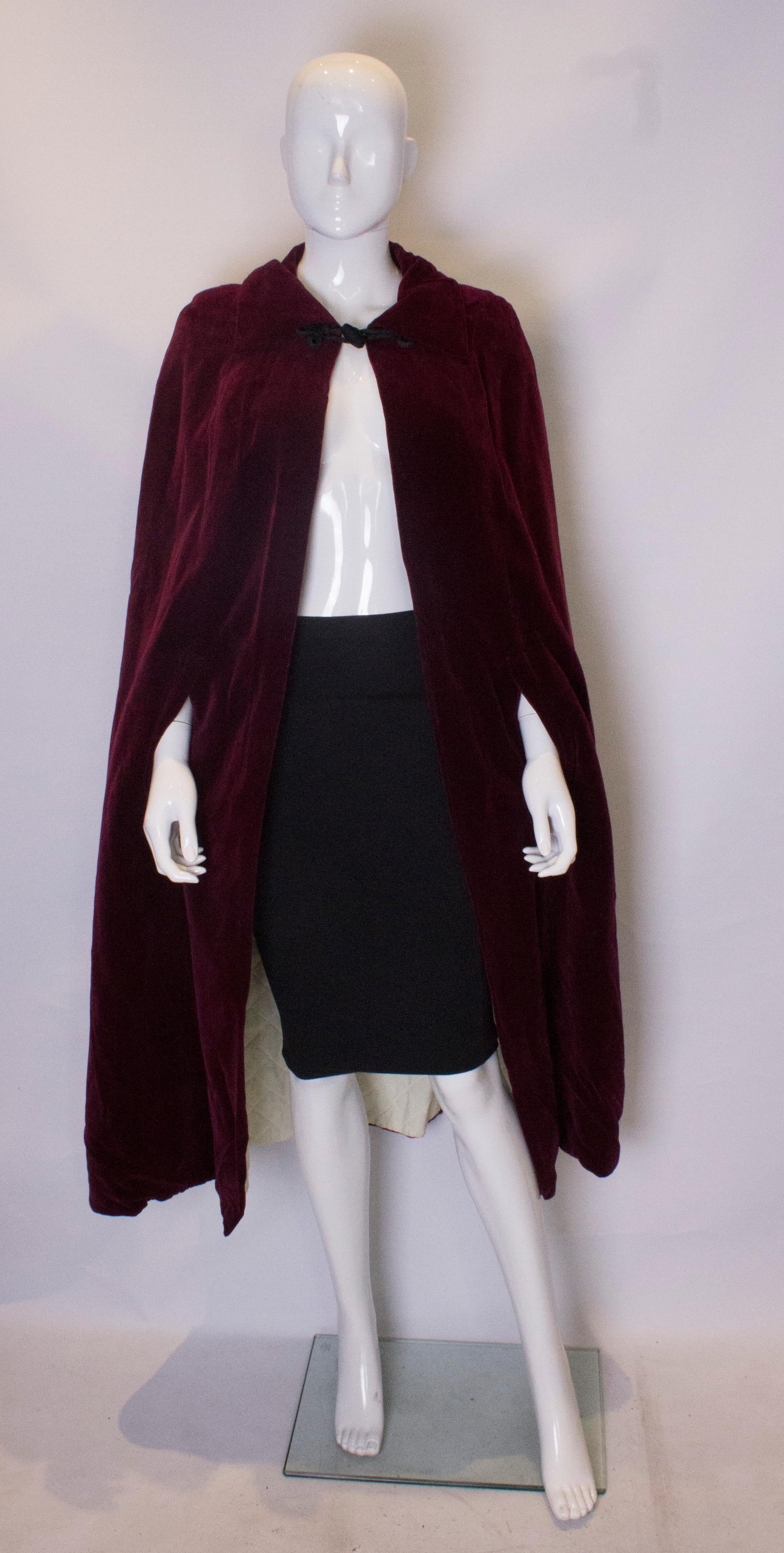 A stunning velvet cape by Quad. The cape is in a burgundy colour velvet with quilted lining. It has a hook and eye fastening at the neck and there are two arm slits lower down. Measurements : shoulder to shoulder 19'', bust up to 41', length 47''