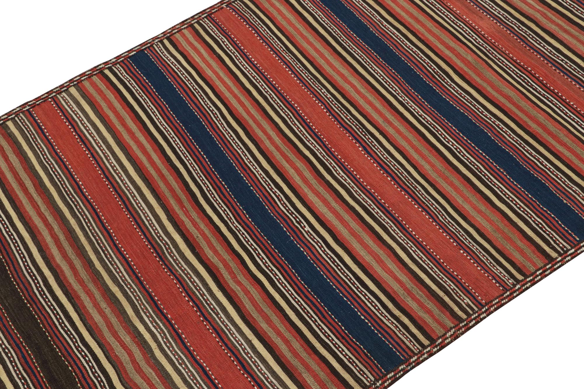 This vintage 4x9 Persian Kilim originates from Quchan city of the Khorasan province— handwoven in wool circa 1950-1960.

Its design is an all over pattern with stripes red, blue, beige, and rich brown, further enjoying mild embroidery. The look is