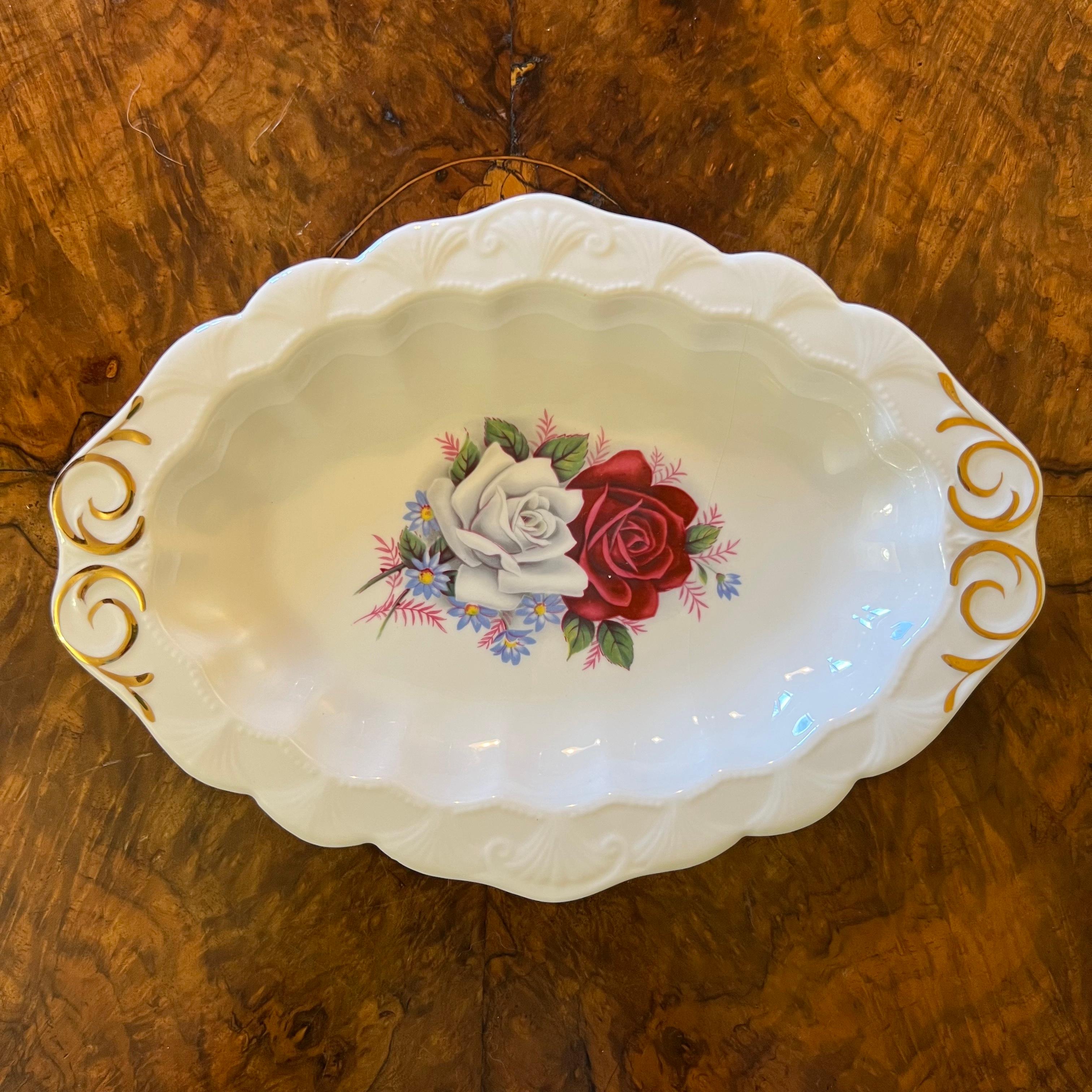 Descripción: Estampado de rosas rojas y blancas con adornos dorados, algo desgastado, estampado Queen Anne

Circa: años 60

Material: Porcelana

País de origen: Inglaterra

Medidas: 2 cm de alto, 24 cm de largo, 17 cm de ancho  

Envío a través de