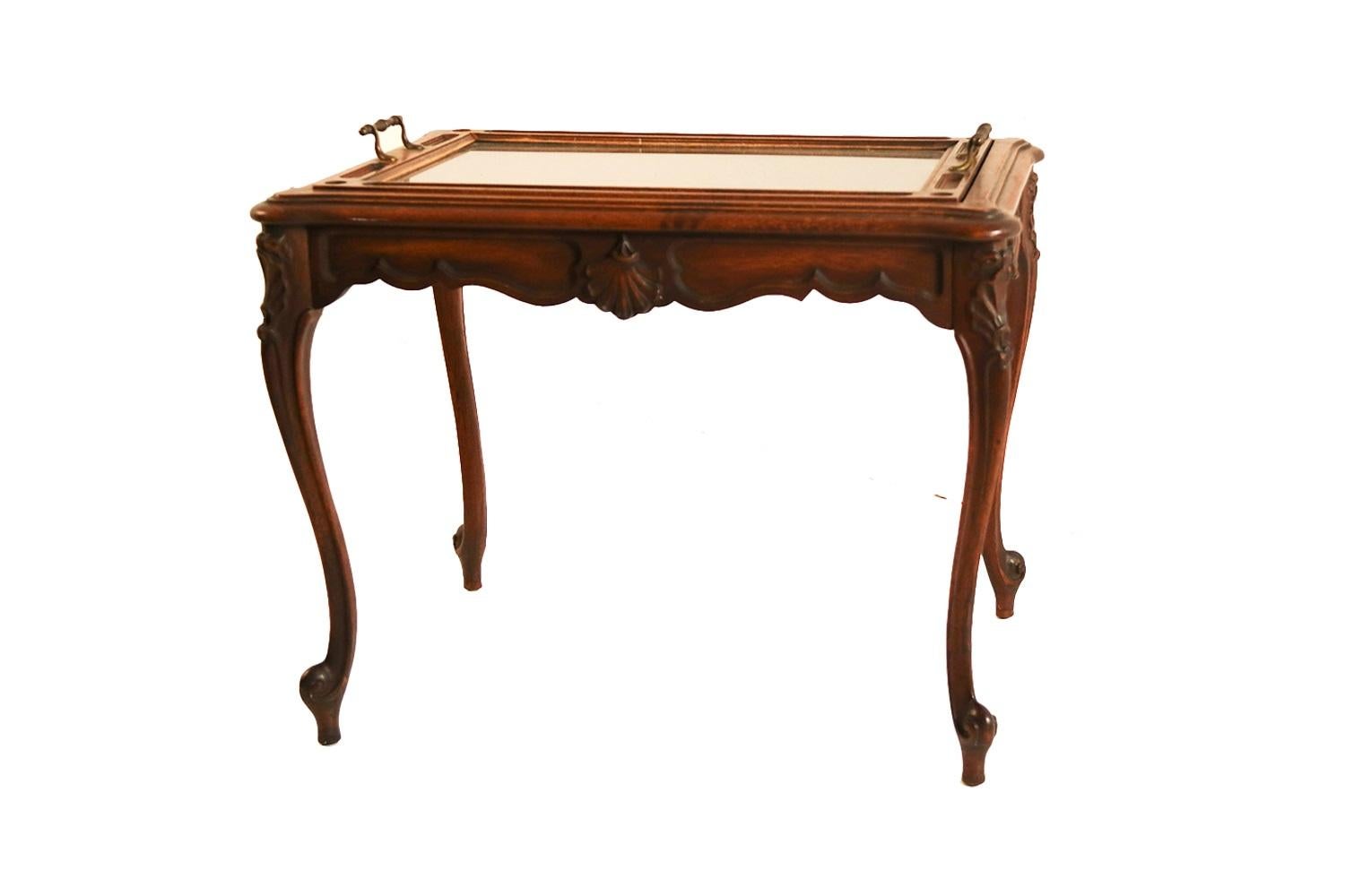 A vintage Queen Anne style mahogany butler, tea table, coffee table with removable glass tray top, early 20th century. This Queen Anne style coffee/ end table features a removable glass center tray inset on a hand carved mahogany frame with