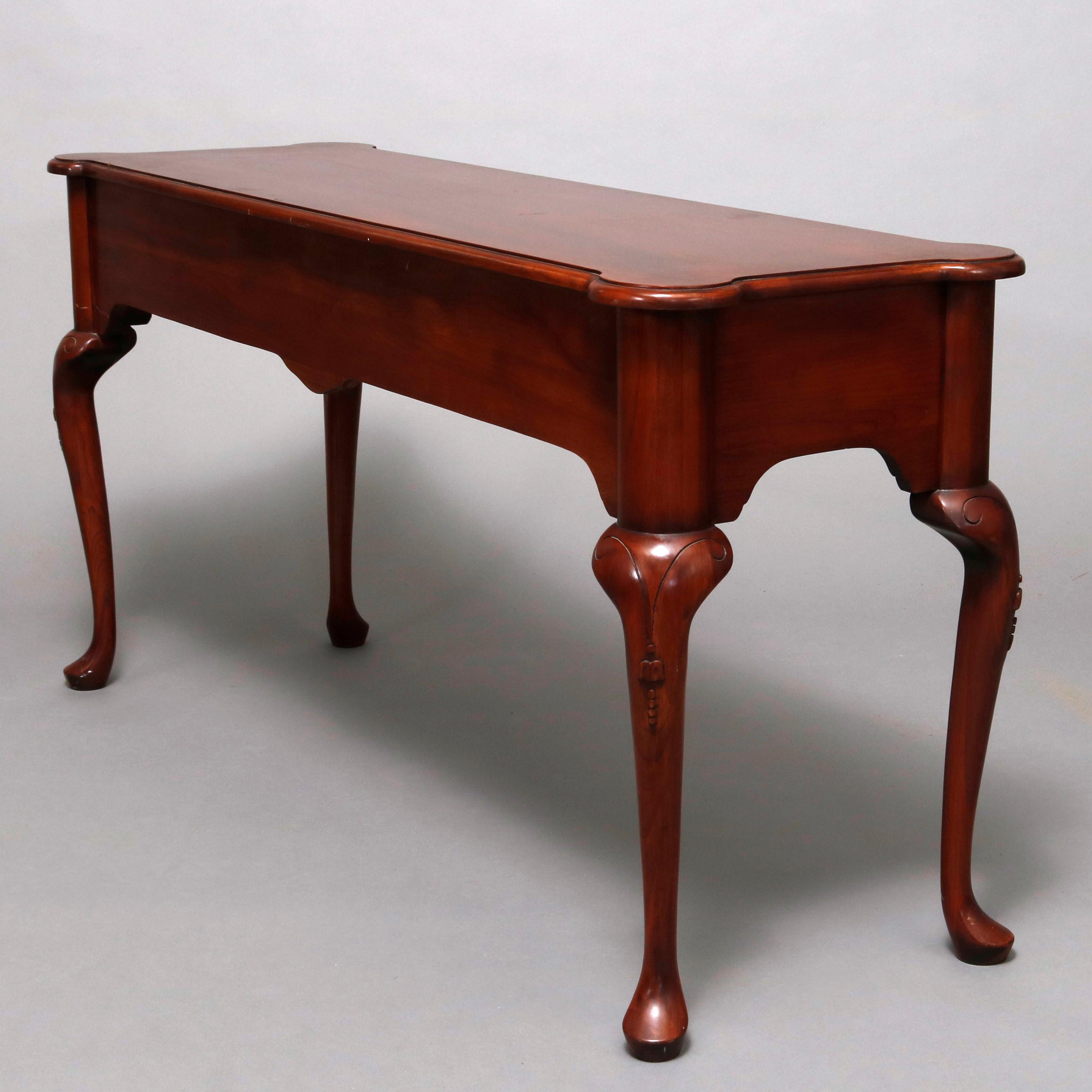 A vintage Queen Anne style sofa table by Harden offers mahogany construction with shaped top surmounting deep apron with two drawers and central carved stylized shell and raised on cabriole legs with incised scroll decoration and terminating in pad