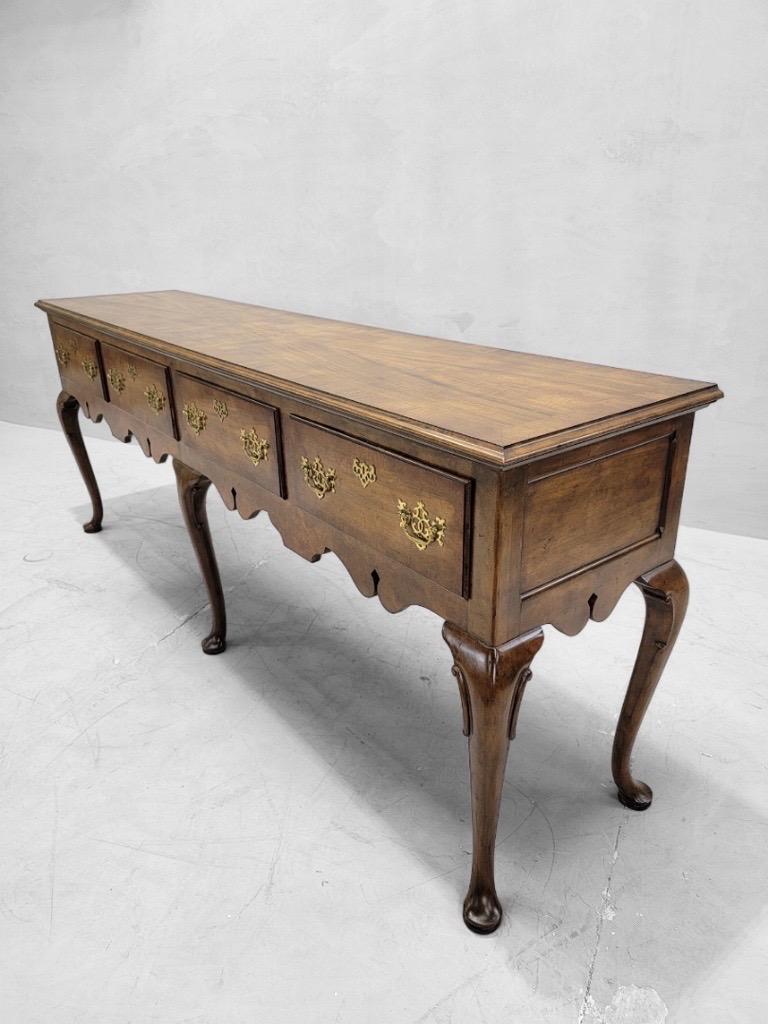 Vintage Queen Anne Style Walnut Console Table/Sideboard with 4 Drawers by Baker Furniture Co.

Cette exquise console vintage est une pièce intemporelle qui respire l'élégance et la sophistication. Fabriquée en bois de noyer de haute qualité, cette