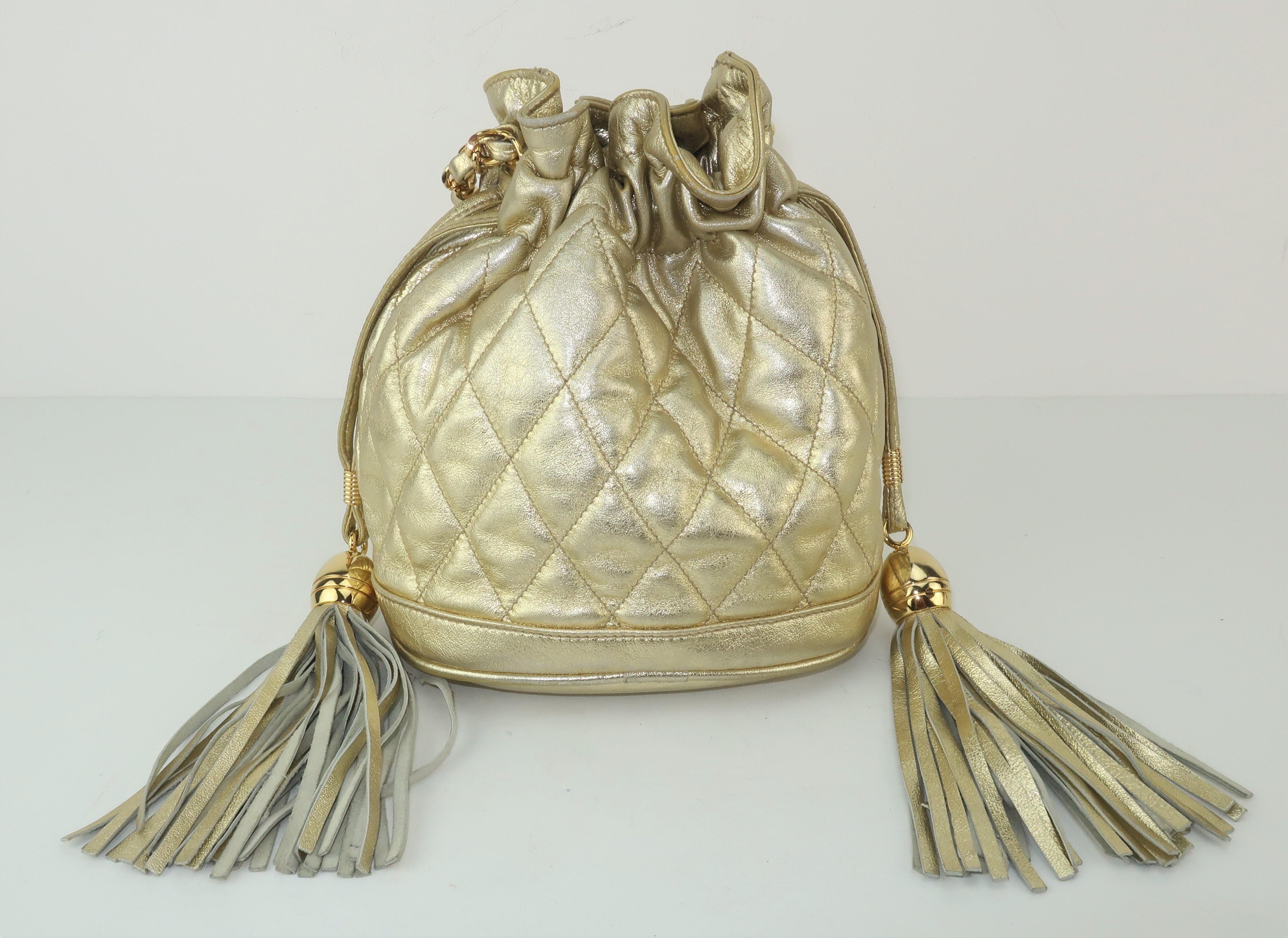 This youthful gold leather hobo handbag made for the Neiman Marcus Collection has quality details with a Chanel look.  The quilted handbag features a drawstring closure with large tassel accents and a chain shoulder strap braided with coordinating