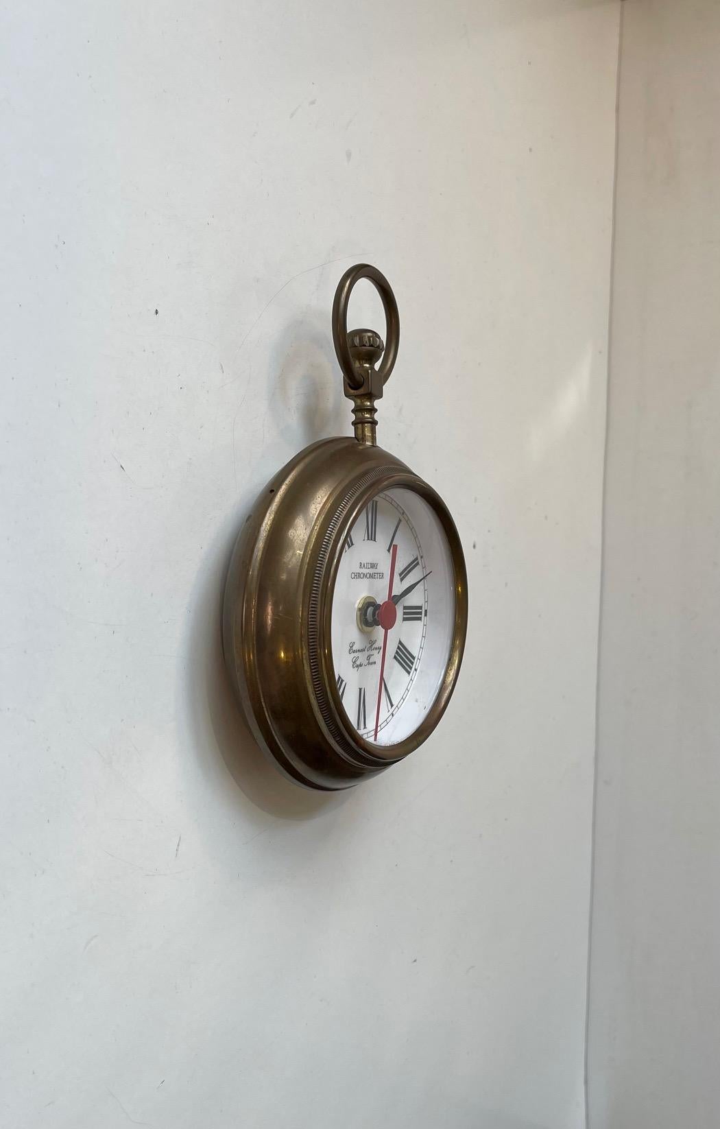 Neuheit aus der Mitte des Jahrhunderts: Jumbo-Taschenuhr oder kleine Wanduhr. Es heißt Eisenbahnchronometer. Das Gehäuse, die Krone und der Ring/Kronenschutz sind aus Messing gefertigt. Zifferblatt mit römischen Ziffern und dem Herstellernamen: