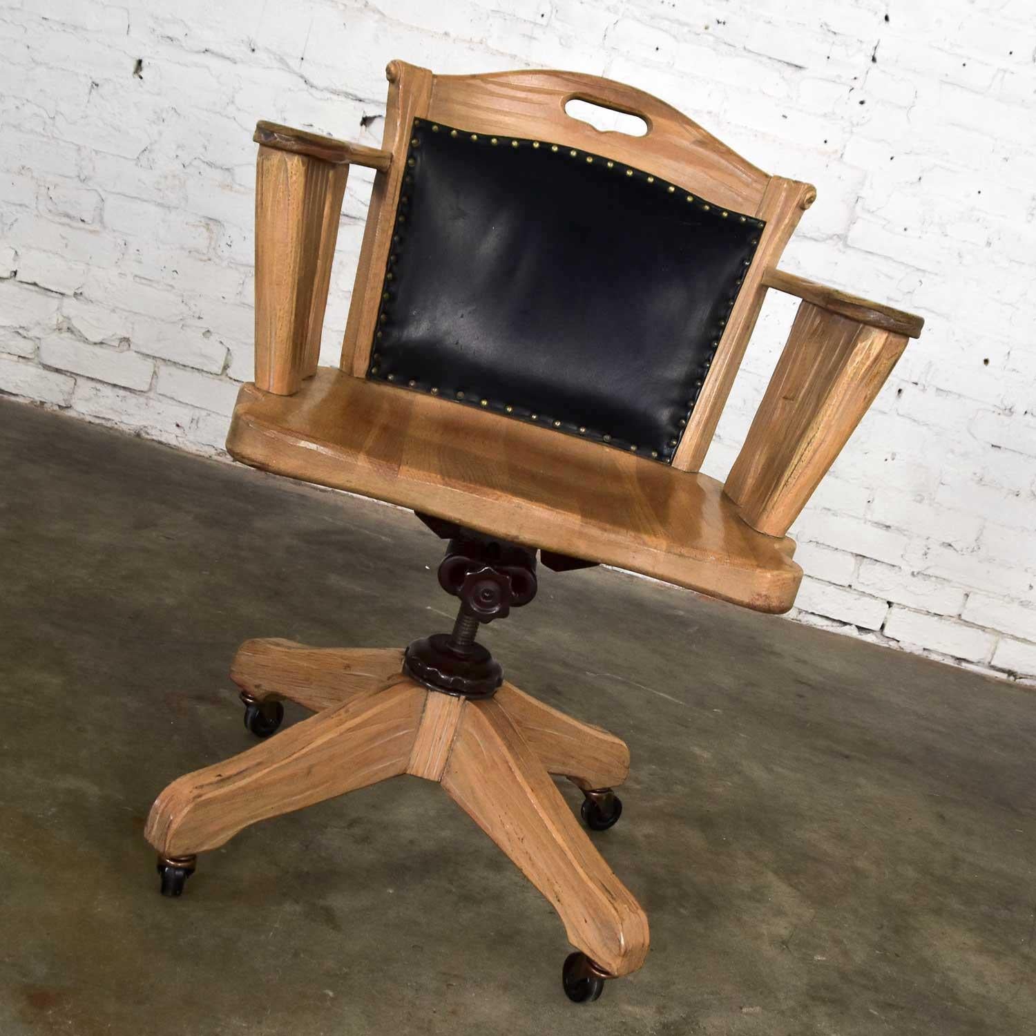 Gorgeous desk chair by A. Brandt comprised of Ranch oak with a honey oak finish, leather back cushion with brass nailhead trim, adjustable painted steel shaft, and rolling casters. Wonderful vintage condition. The casters and sockets have been