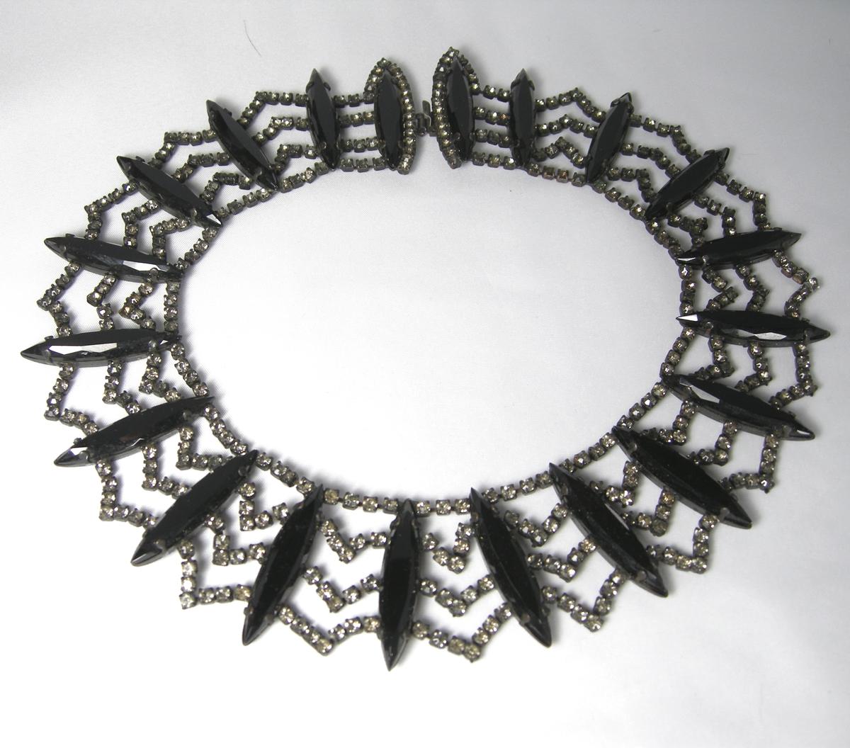 This rare vintage 1950s signed Hattie Carnegie collar necklace has 20 black glass marquise stones … each divided by four rows of rhinestones.  It has a slide-in clasp.  It measures 16” long x 1-1/2” wide in a Japanned metal finish.  It is signed