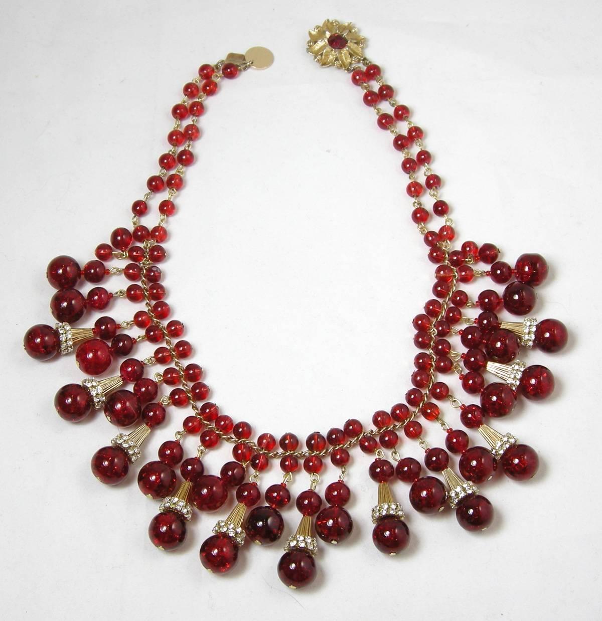 This vintage rare old Czech glass necklace is from the 1930s and leads down to round red glass beads alternating with ribbed rhinestone capped beads that hang down giving a bib look.  The slide in clasp is a gold tone flower with a red glass center.