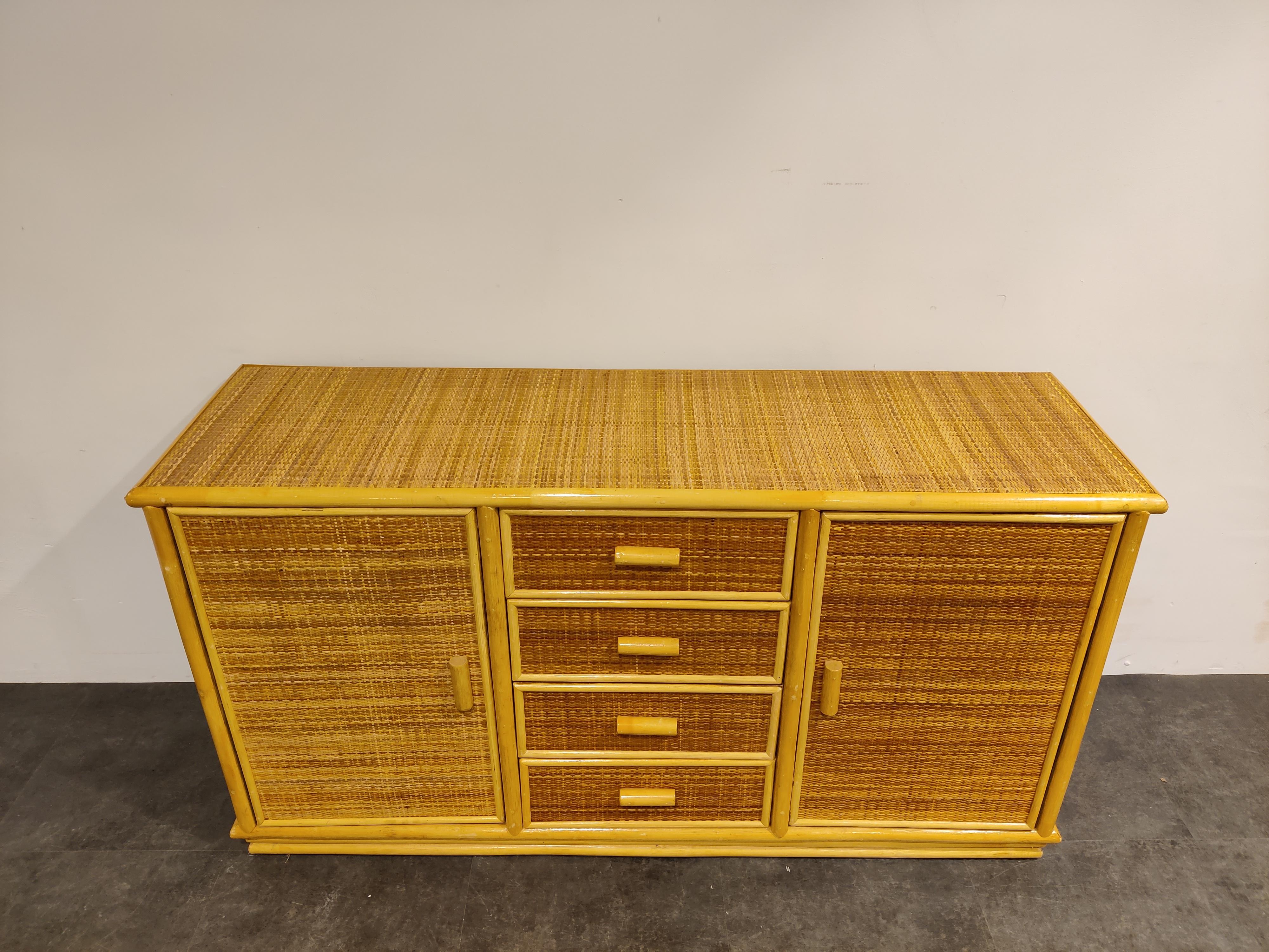 Elegant bohemian style bamboo and rattan sideboard with two doors and four drawers.

Very good condition, good quality sideboard.

1970s - France

Dimensions:

Lenght: 150cm/59.05