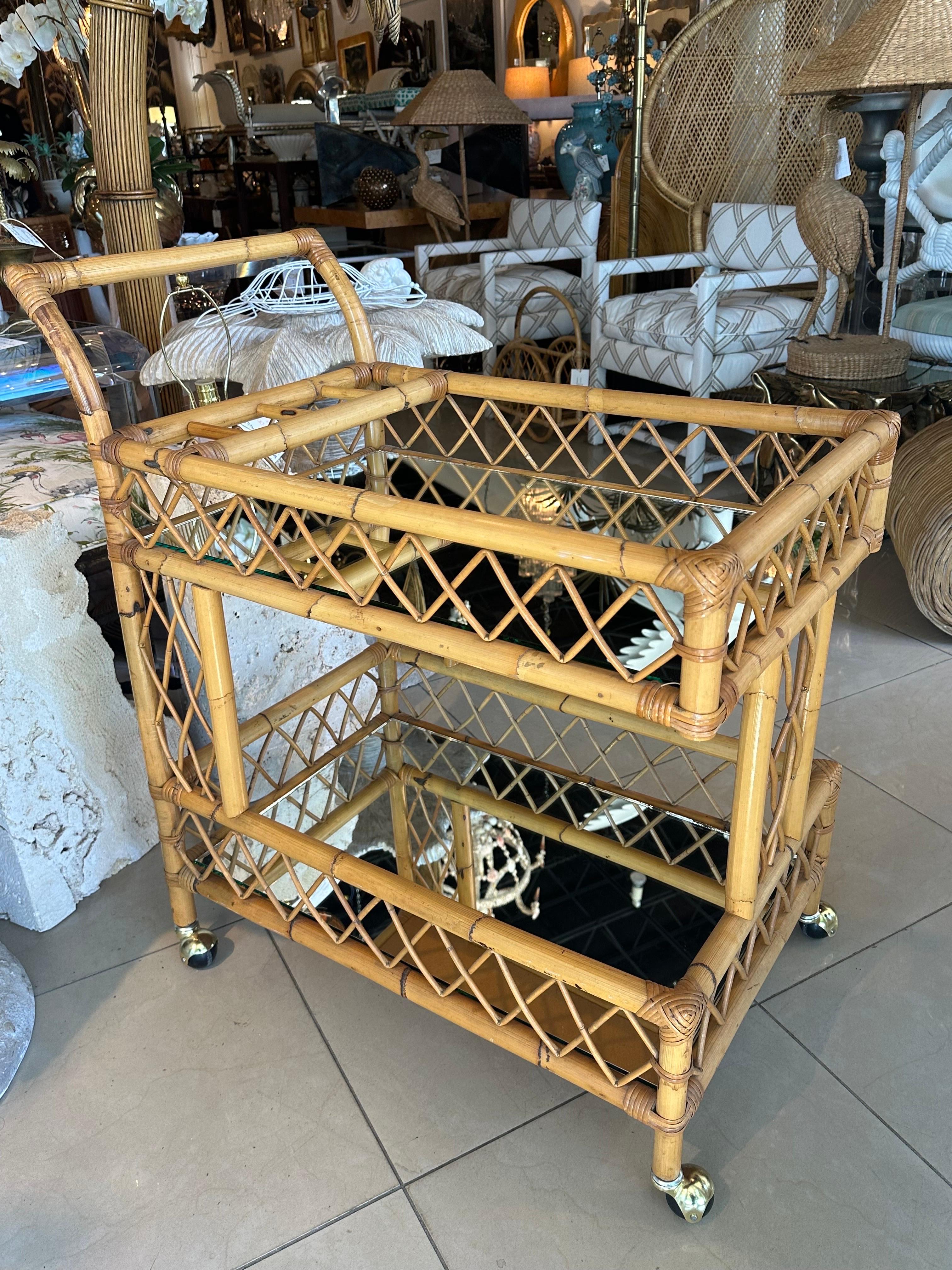 Vintage Mid Century Italian rattan bamboo, two tier bar serving trolley cart. New mirror has been placed on both shelves. New brass castors. There is no damage or defects to the original finish natural rattan. Dimensions: 36 H x 19.5 W x 33 D. 