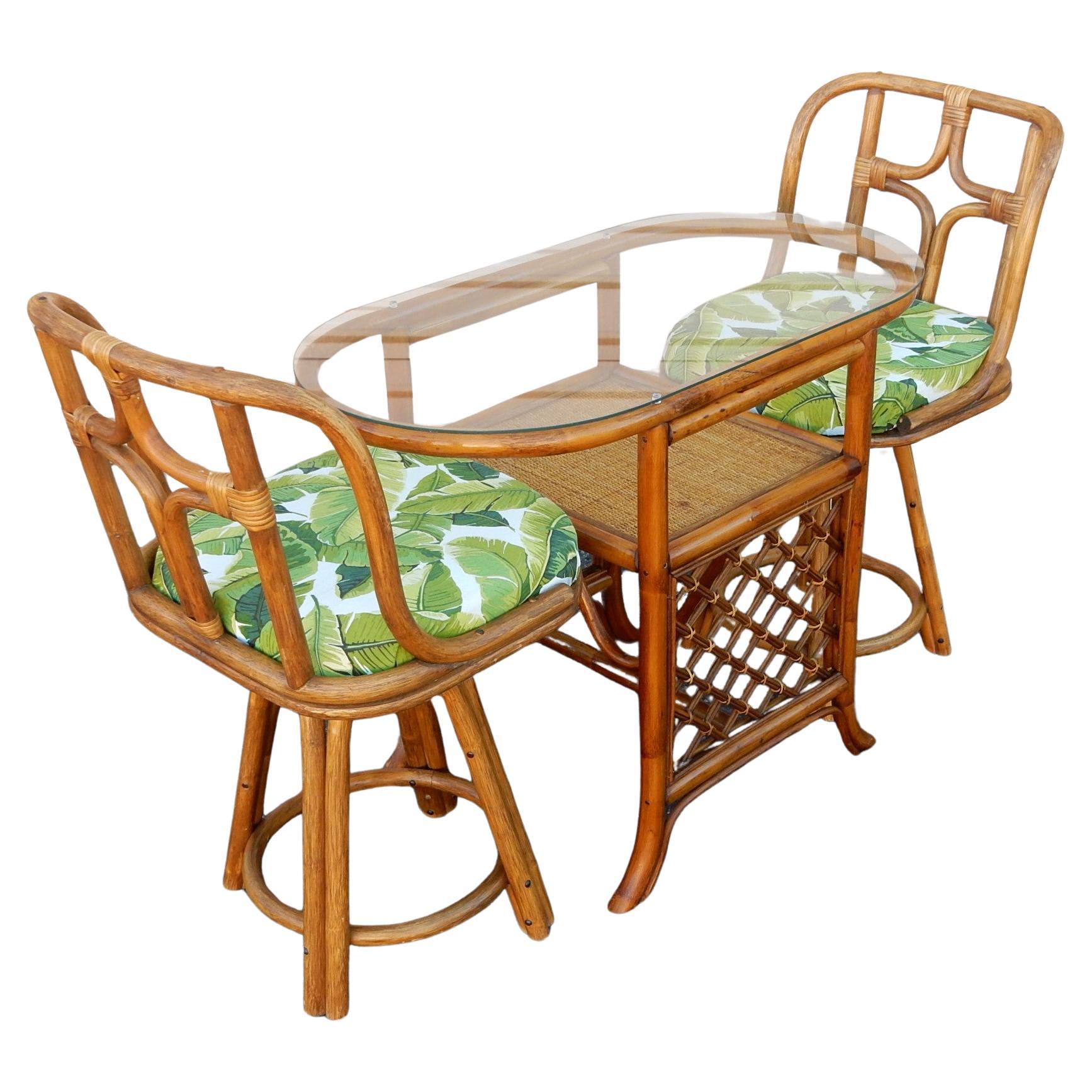 This lovely, modestly scaled rattan and cane set is from in the late 1970s. Includes a small oval glass top table and two swivel chairs. Elegantly crafted by Asian artisans of bend cane and reed.
This set would make a perfect breakfast or game table