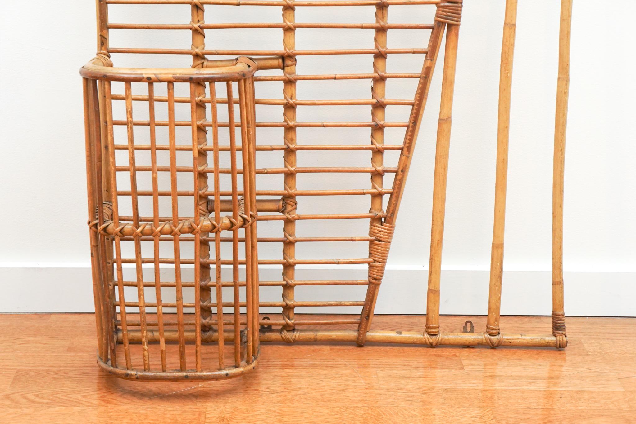 Designed by French furniture designer Louis Signot circa 1960s, this vintage rattan coat rack with umbrella stand is as decorative as it is useful. The design combines vertical and rounded rattan elements that are intricately fastened to include