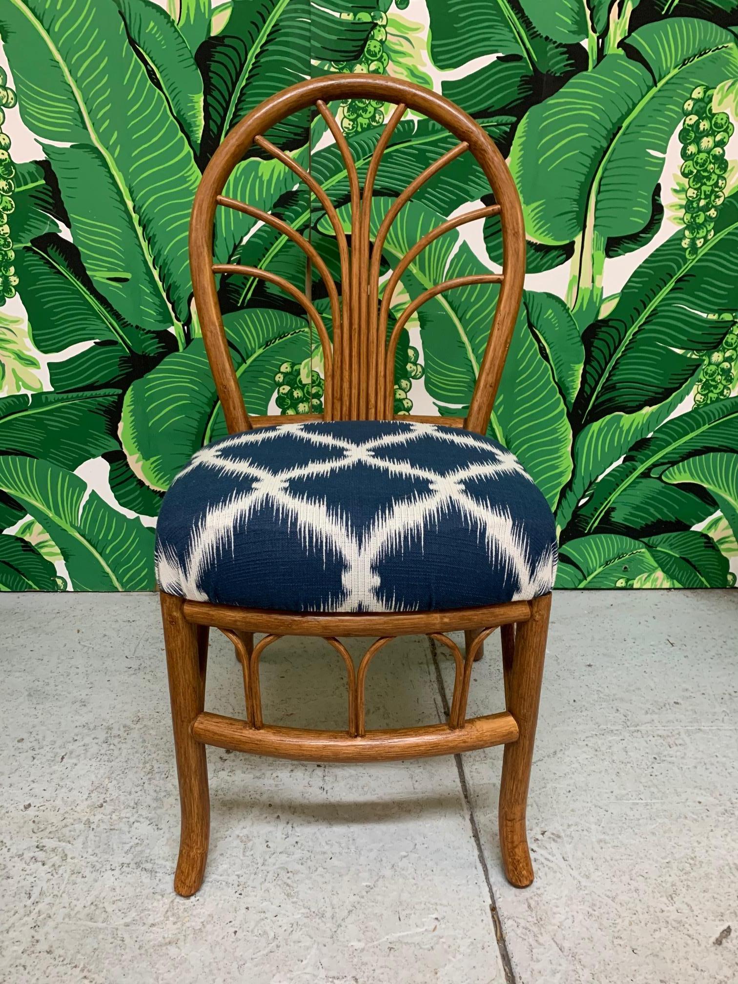 Set of four vintage rattan dining chairs includes two side chairs and two armchairs. Upholstered in blue and white modern fabric. Very good condition with only very minor imperfections consistent with age. Side chairs measure 16.5