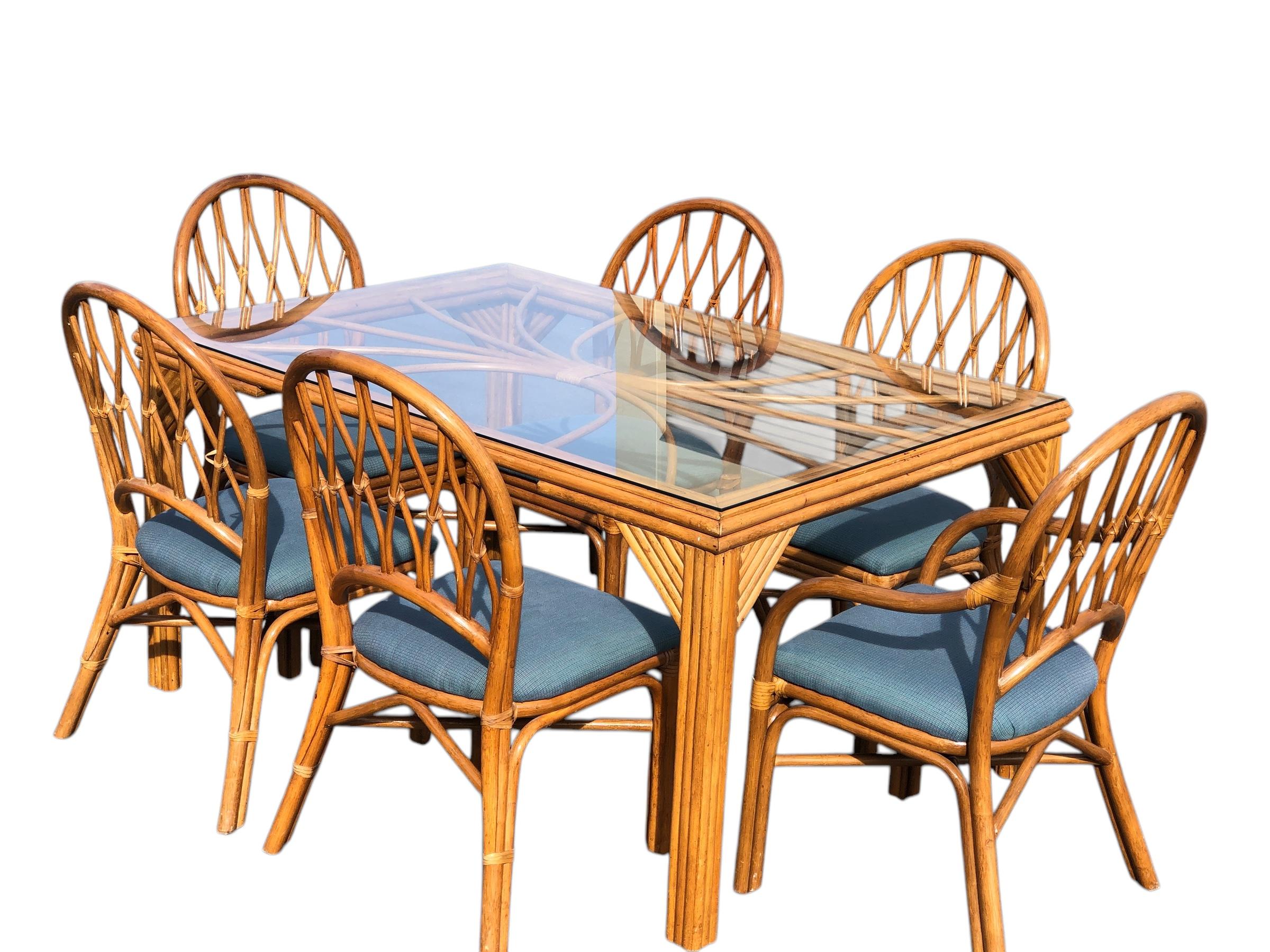 Set da pranzo in rattan vintage attribuito a John McGuire composto da un tavolo da pranzo in rattan con ripiano in vetro e sei sedie da pranzo. Ci sono cinque sedie laterali e una poltrona. Questi sono avvolti intorno alle articolazioni con corde di