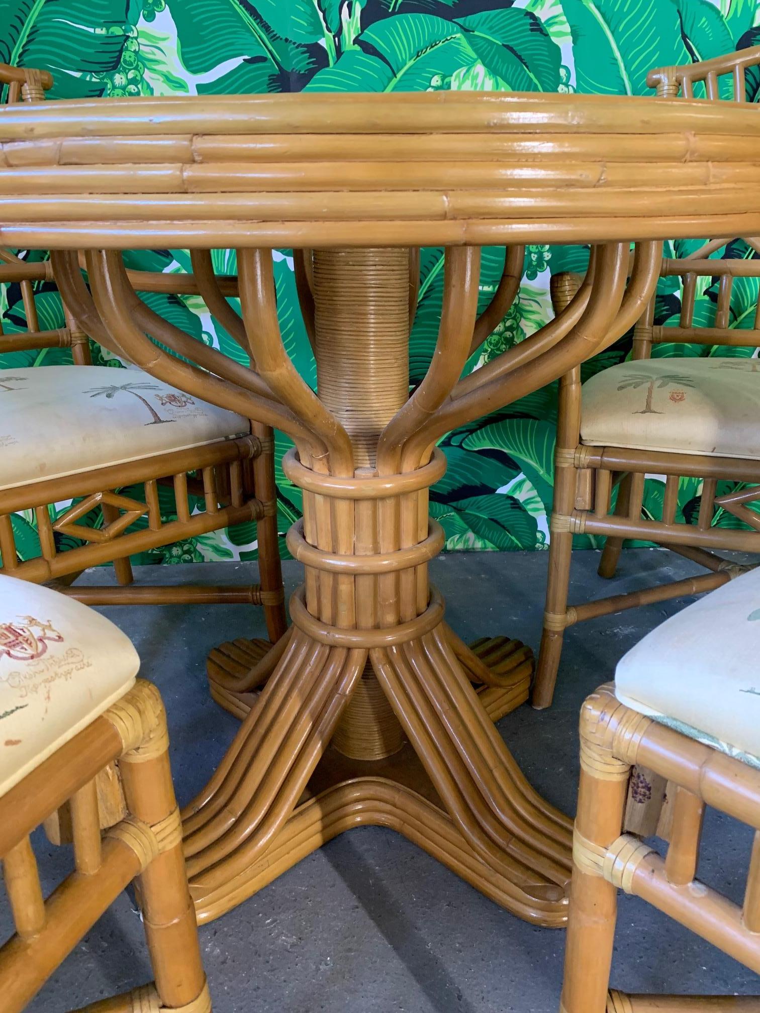 Vintage rattan dining set includes table and four chairs. Two armchairs and two side chairs. chinoiserie style design on chair backs, and woven rattan tabletop. Table and chairs in very good vintage condition, with minor imperfections consistent