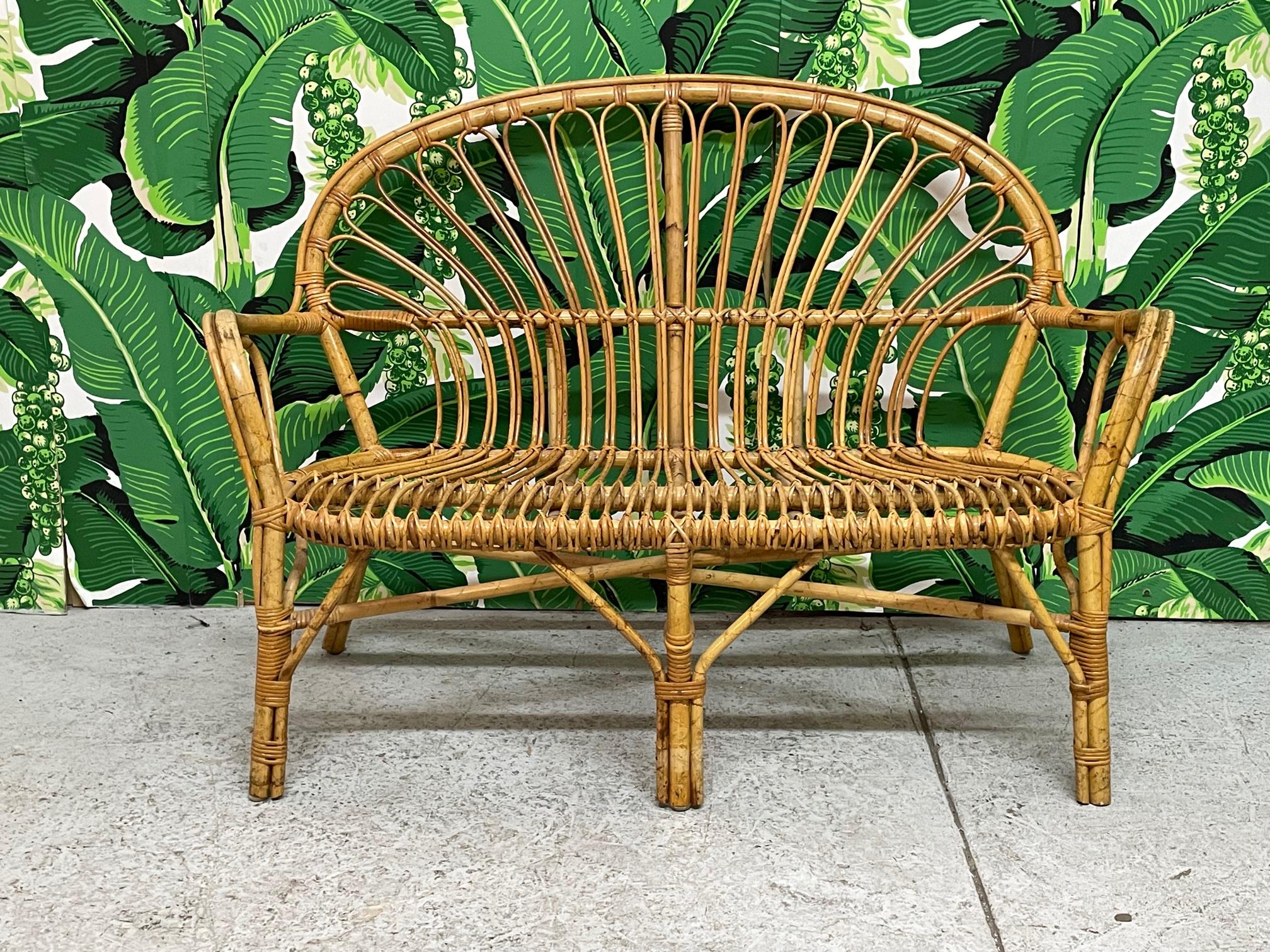 Vintage rattan loveseat or settee features intricate fretwork and a rich, warm finish. We have 5 of these available. Structurally sound and in good condition with minor imperfections consistent with age. May exhibit scuffs, marks, or wear, see