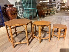 Juego vintage de tres taburetes hexagonales y mesas auxiliares de ratán, años 50